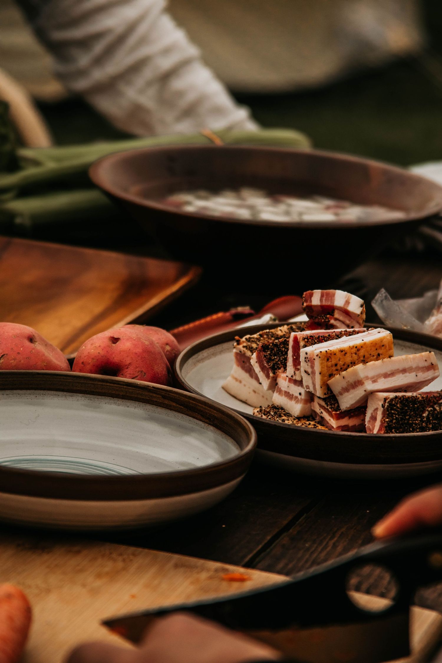 Rustic plates with sliced bread and fruit arranged on a dark wooden table in moody lighting.