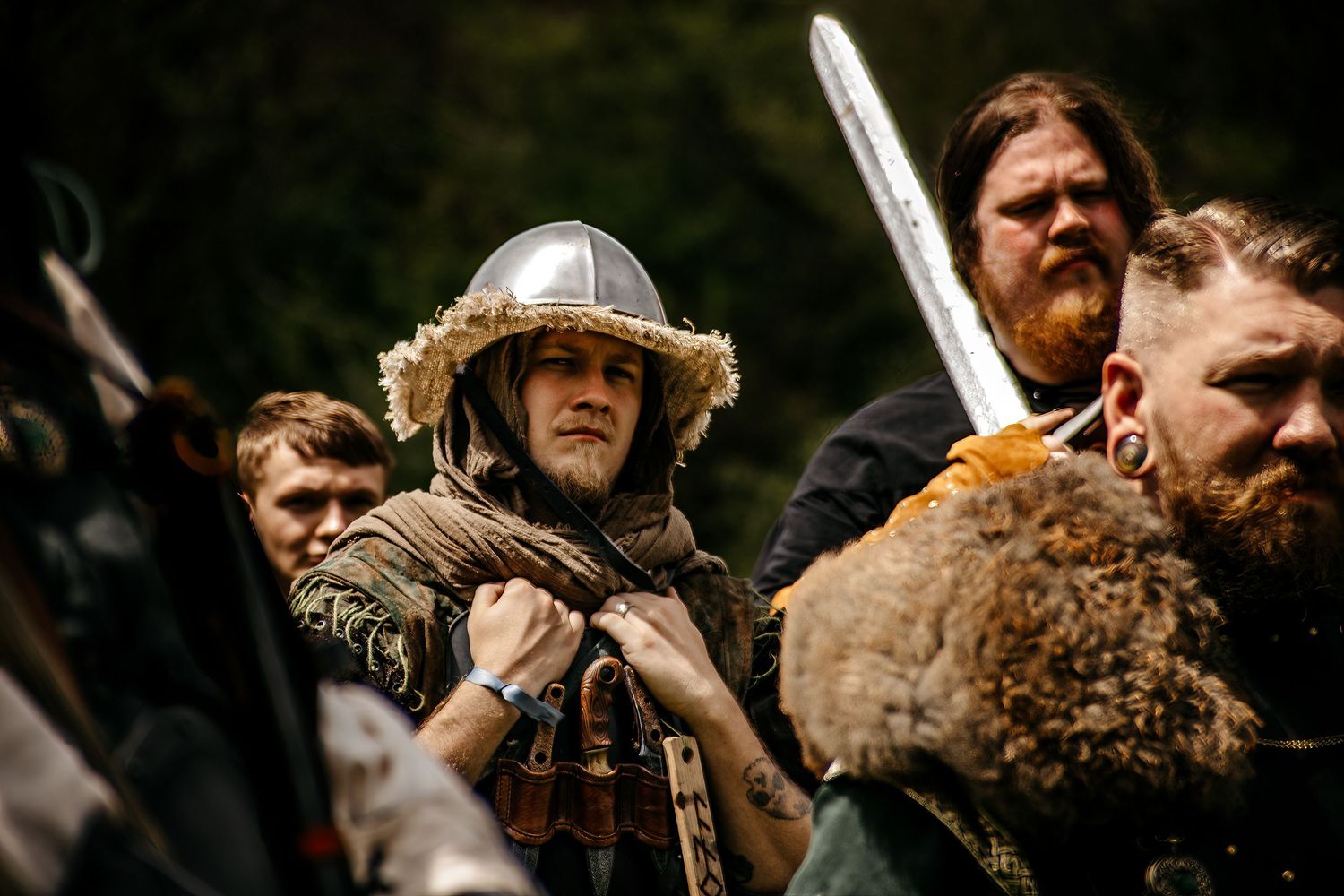 Medieval Viking reenactors in armor and helmets wielding swords during a historical battle reenactment outdoors.