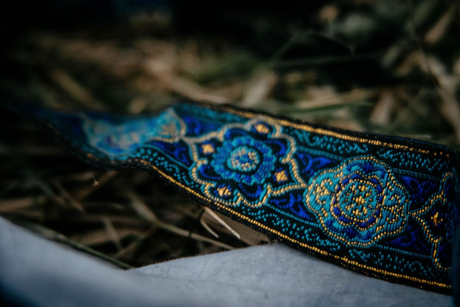 Close-up shot of decorative blue and gold embroidered trim ribbon against a dark background.