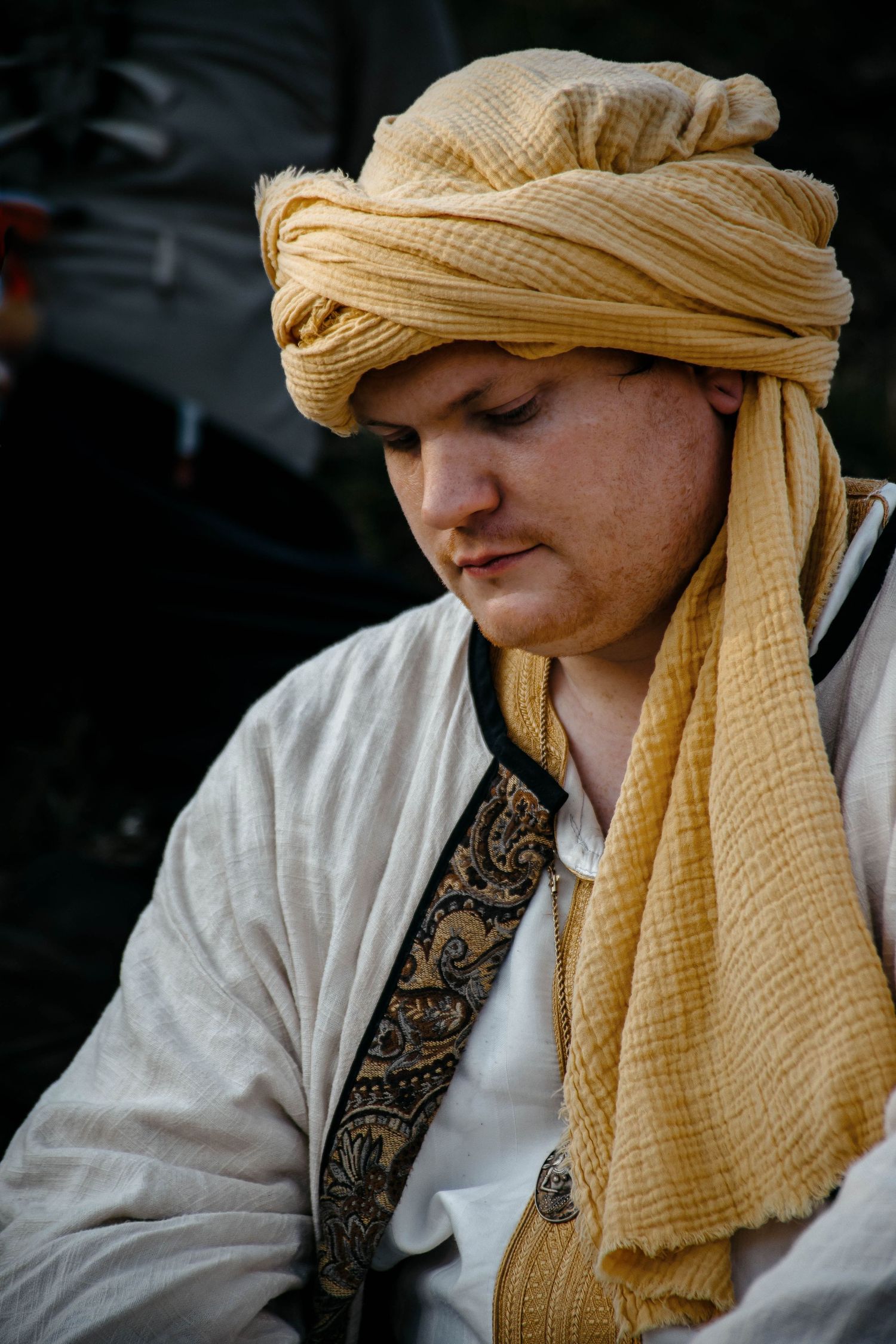 A series of close-up shots showing a person wearing a beige head wrap and white embroidered garment against a dark background.