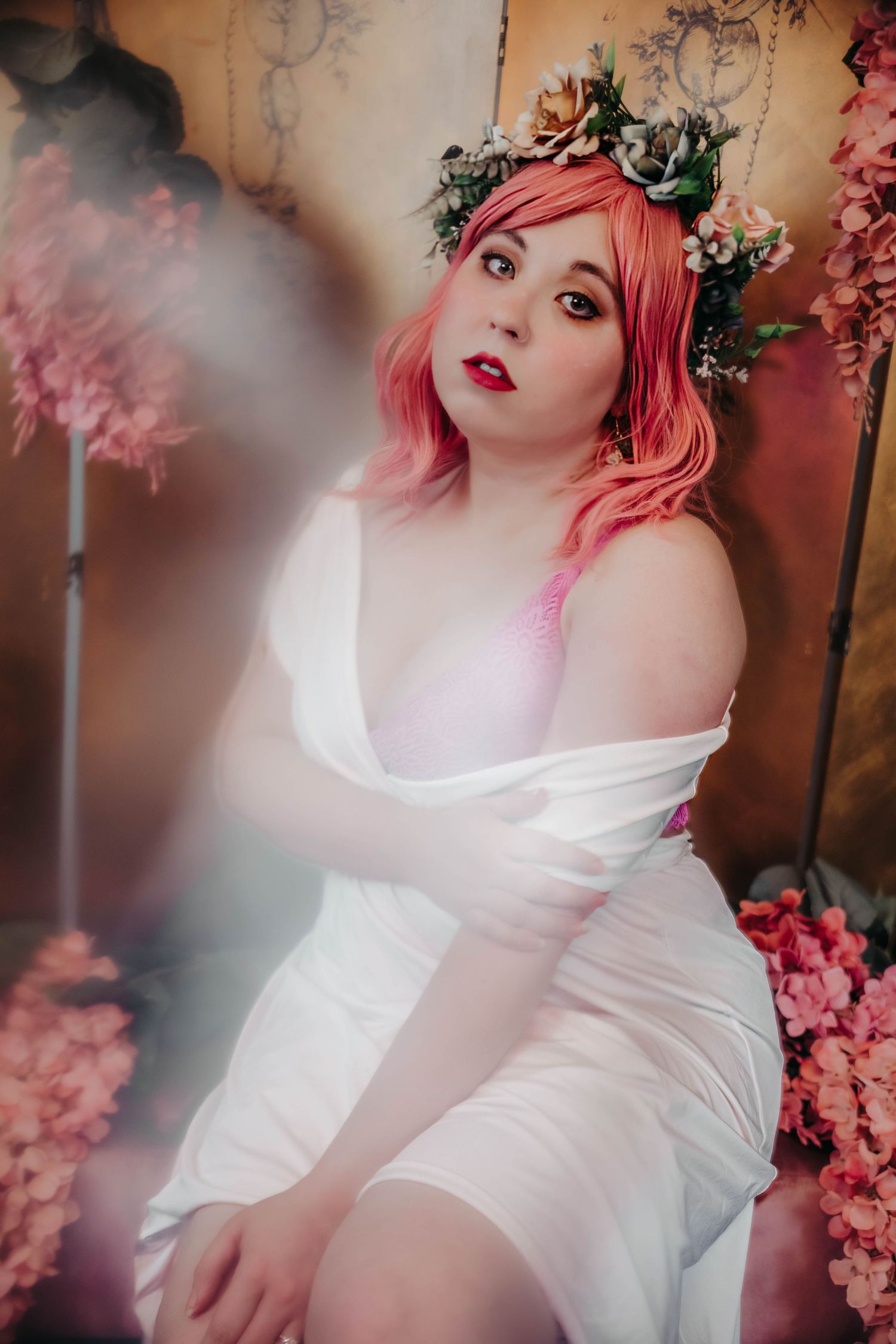 Ethereal portrait series with pink cherry blossoms featuring dreamy lighting and flowing white fabric in romantic setting.