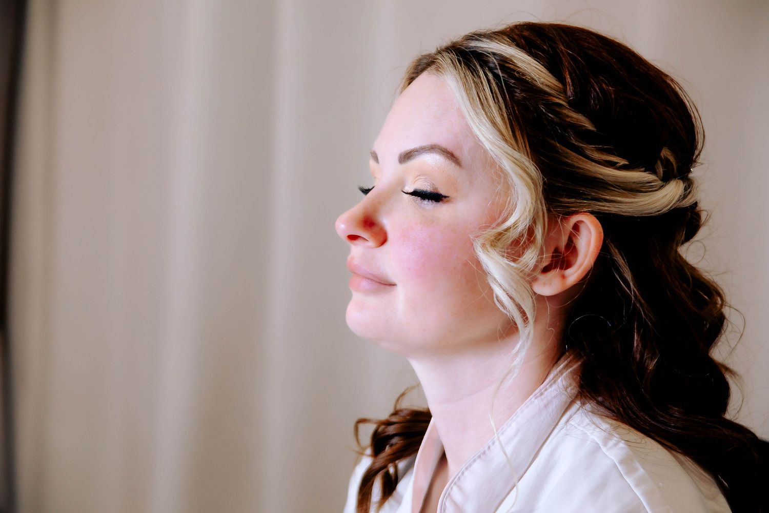 Side profile of bridal beauty with elegant updo hairstyle and natural makeup.