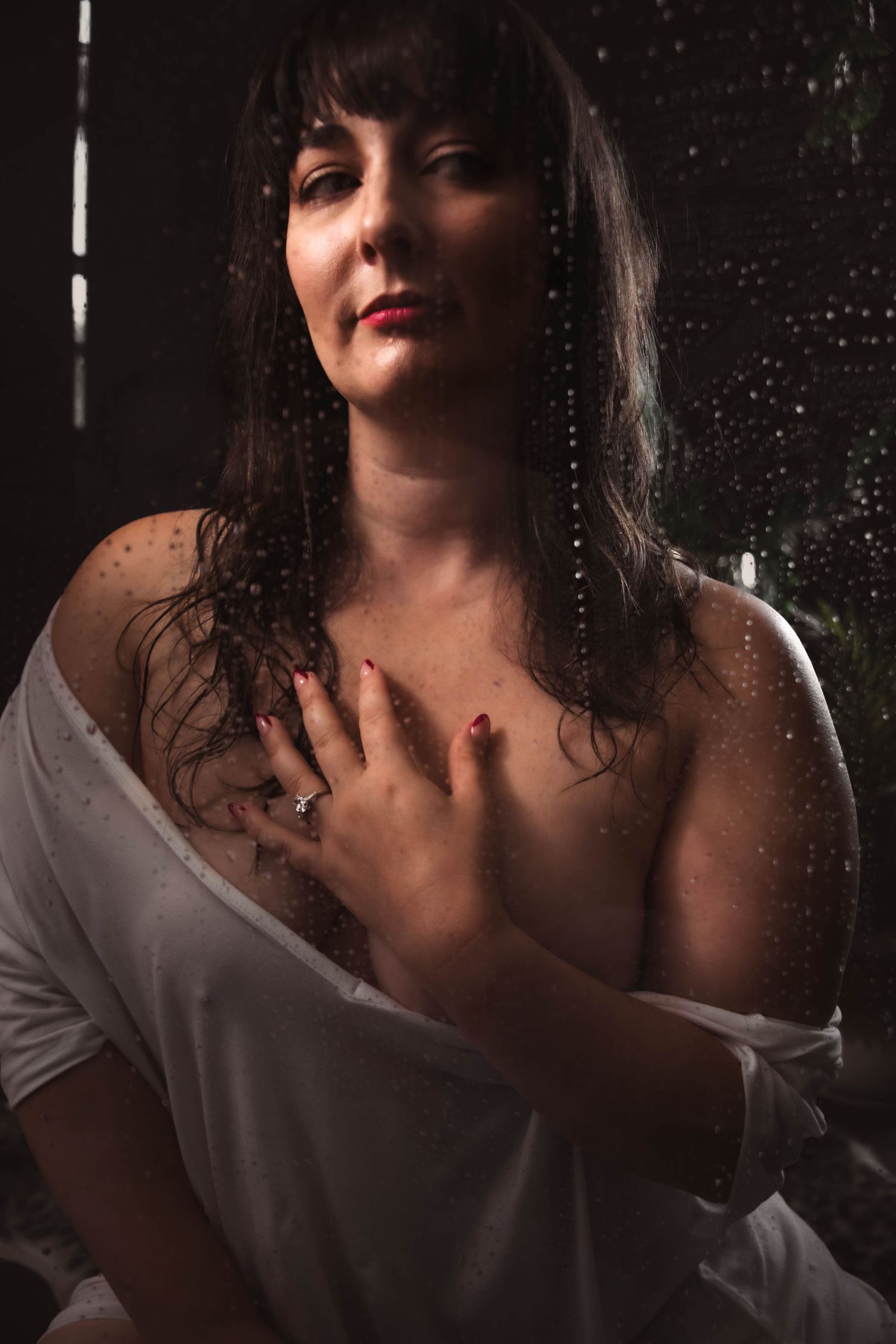 Dramatic studio portrait with rain effects and moody lighting.