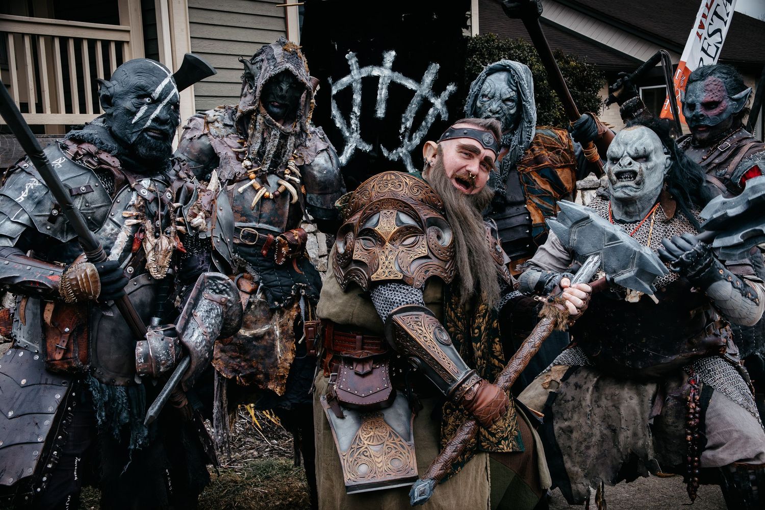 Cosplayers dressed in post-apocalyptic costumes with masks and weapons pose together at a convention.