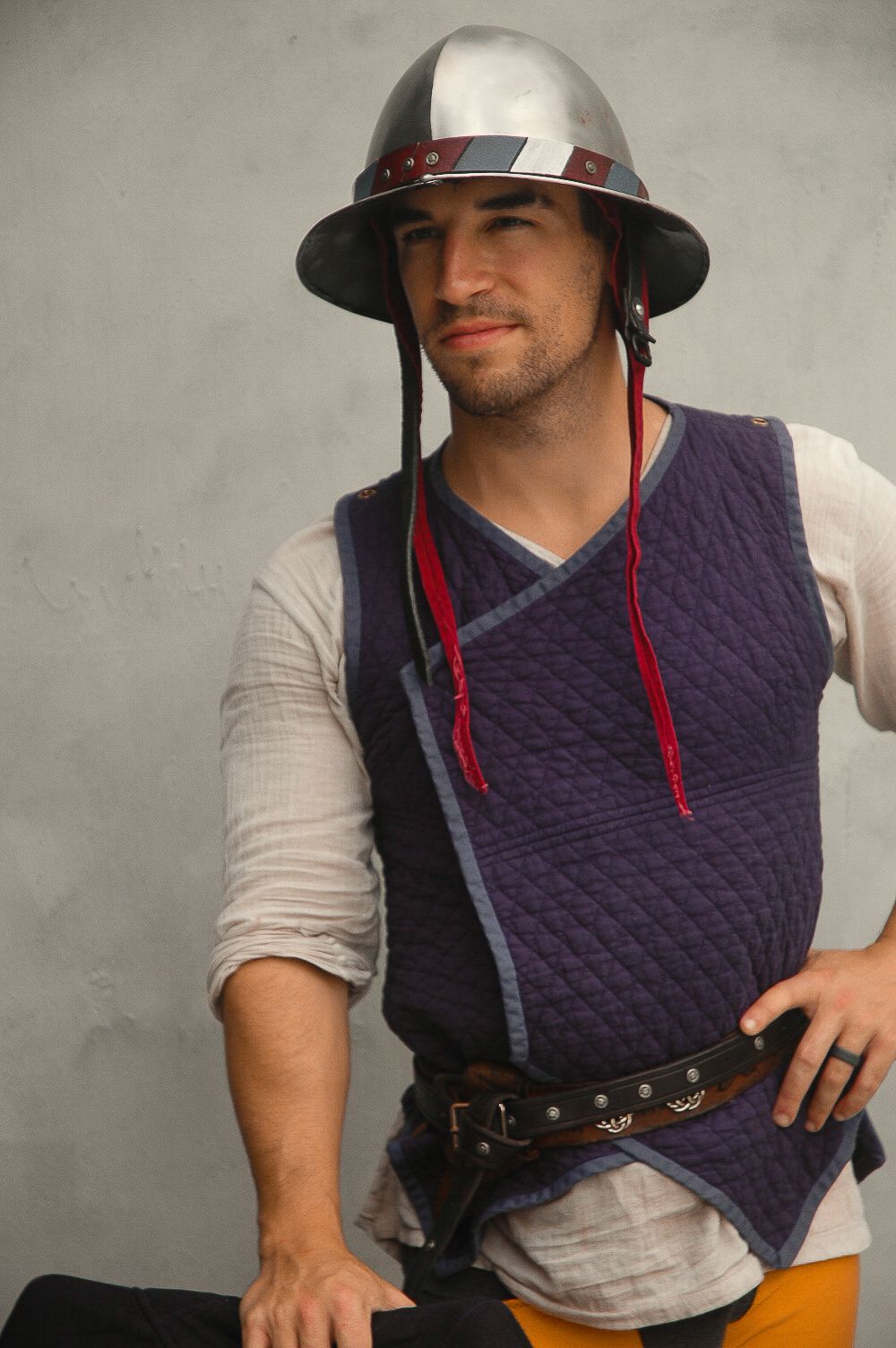 Person wearing a quilted purple vest with red drawstrings and a gray t-shirt demonstrates different angles of the garment.