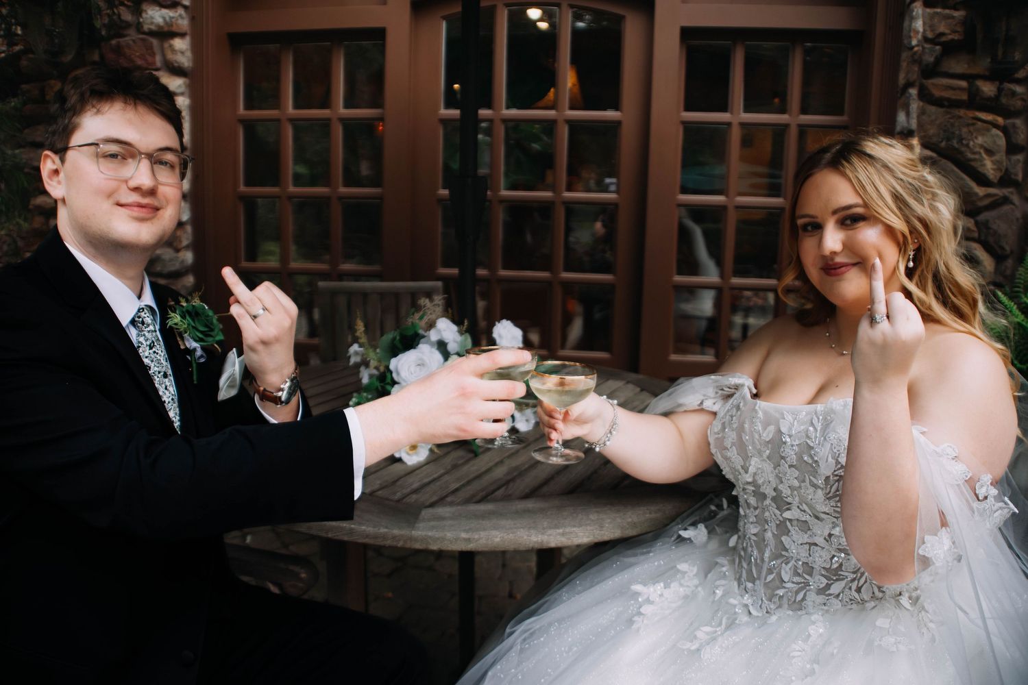 Newlyweds share a toast at a rustic wedding venue, with the bride wearing a sparkly ballgown dress.