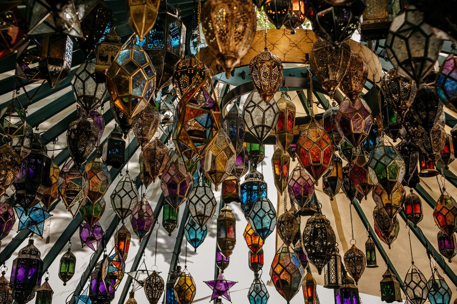 Colorful Moroccan lanterns and ornate metal lamps hanging in a vibrant market display.