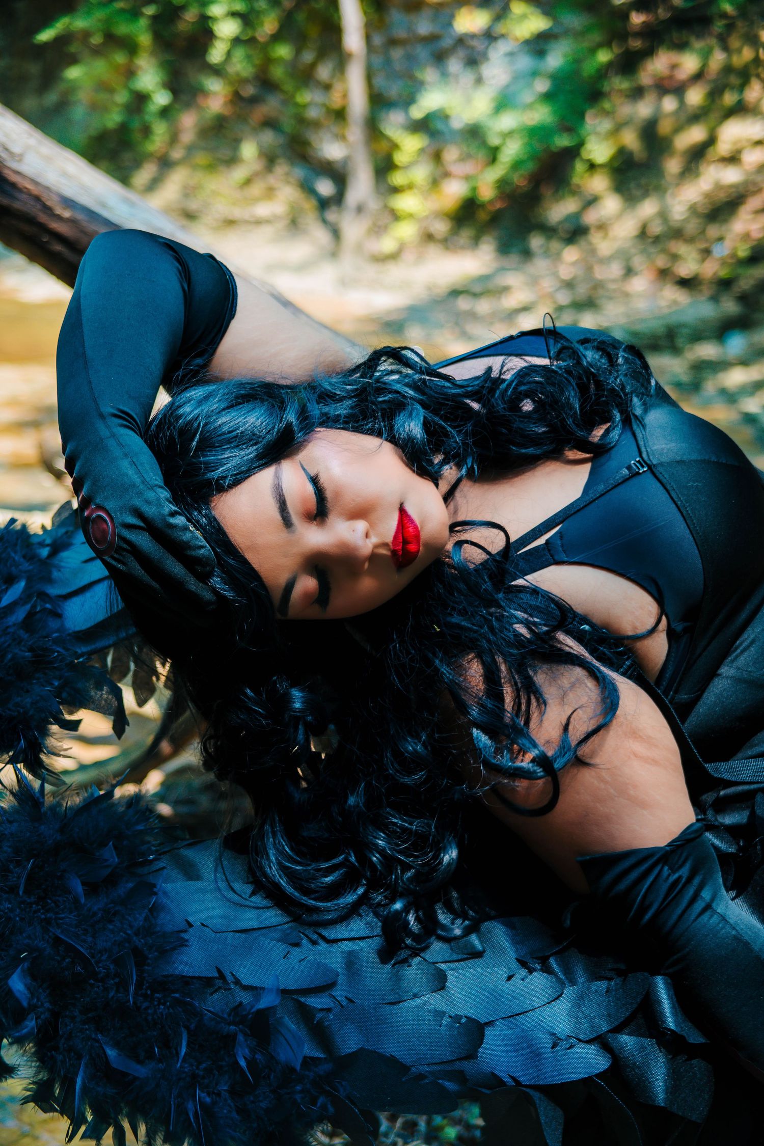 Gothic fashion shoot with black dress and curls against natural outdoor setting.