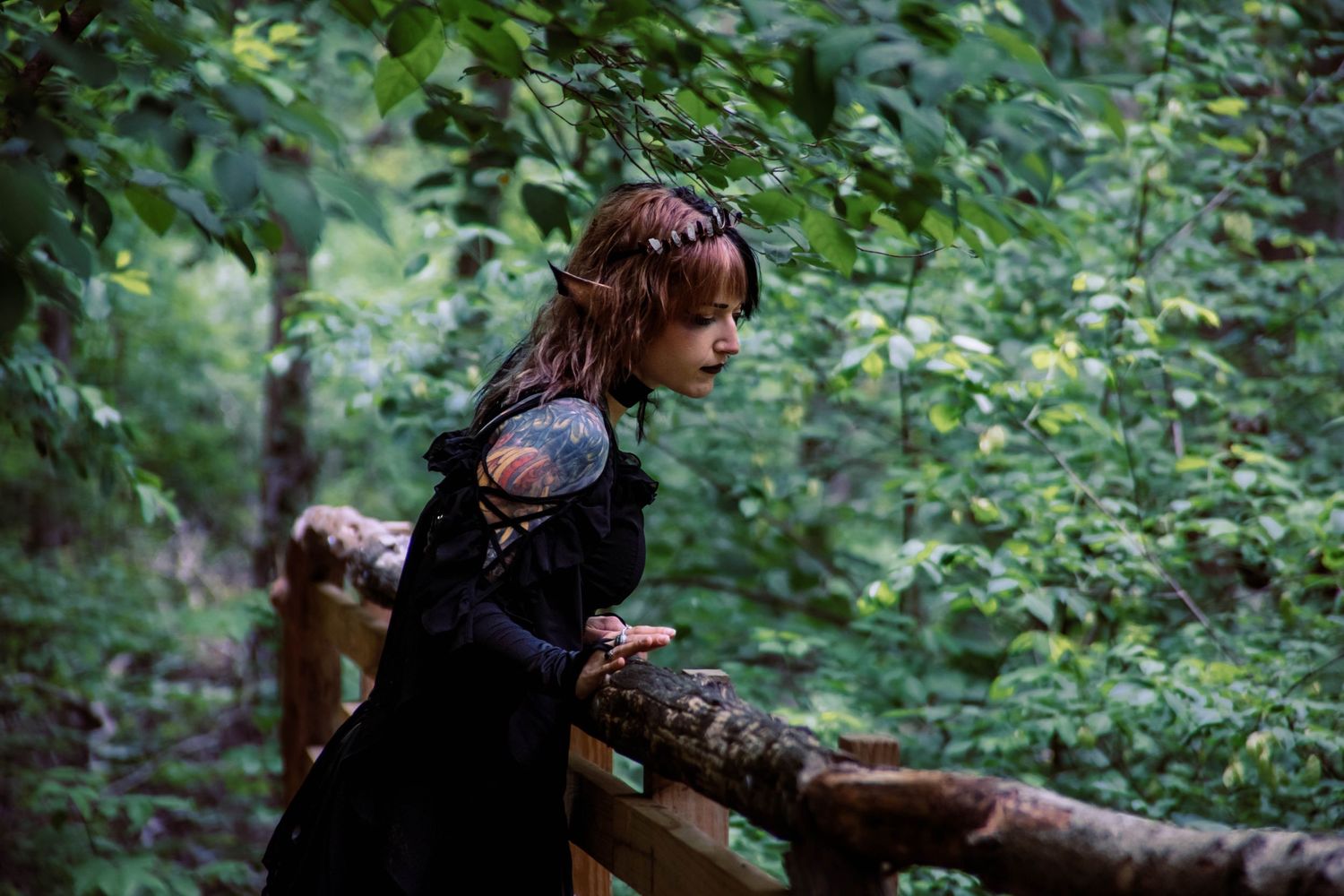 A person rests against a fallen tree trunk in a lush woodland setting.