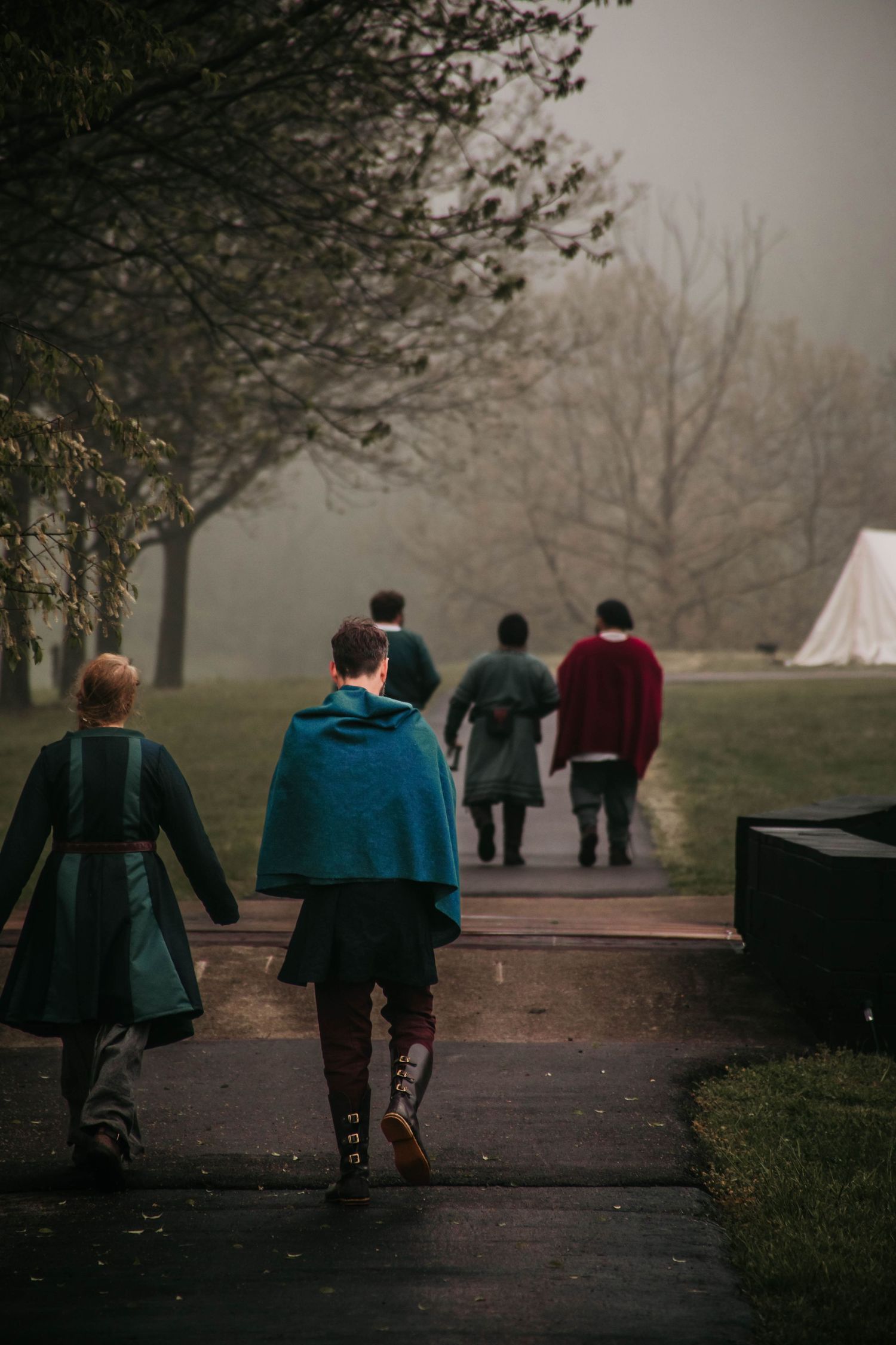 A group of people walking together on a foggy path through a park on a moody autumn day.