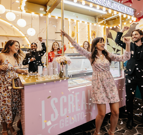People celebrating at an ice cream shop counter with confetti and excitement in the air.