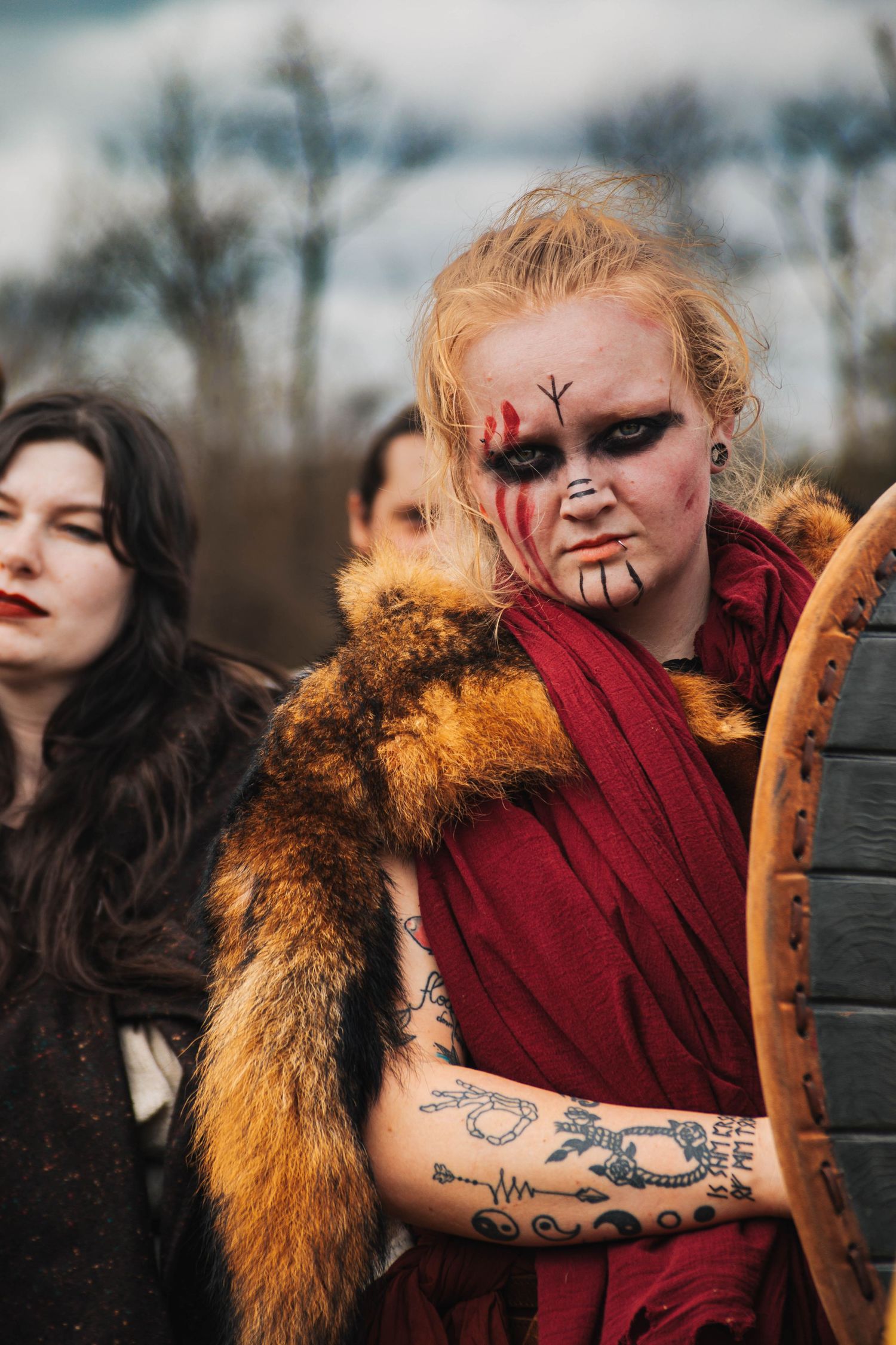 Artistic fashion photo series showing dramatic makeup, burgundy clothing and fur trim in moody outdoor setting.