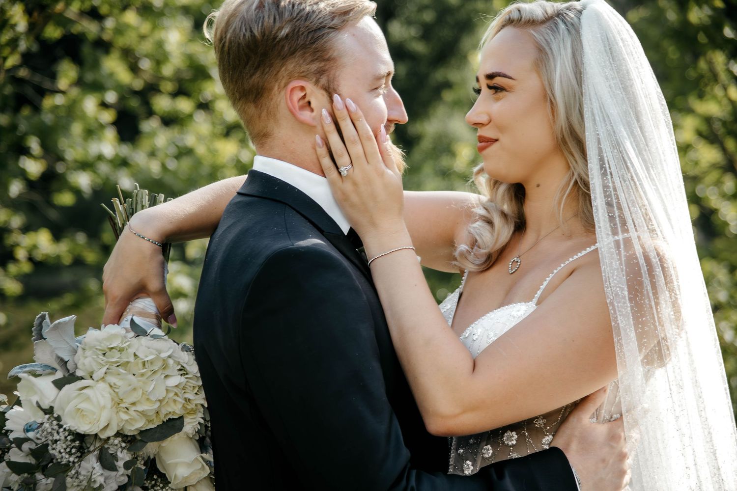 Tender wedding moment captured against natural outdoor backdrop.