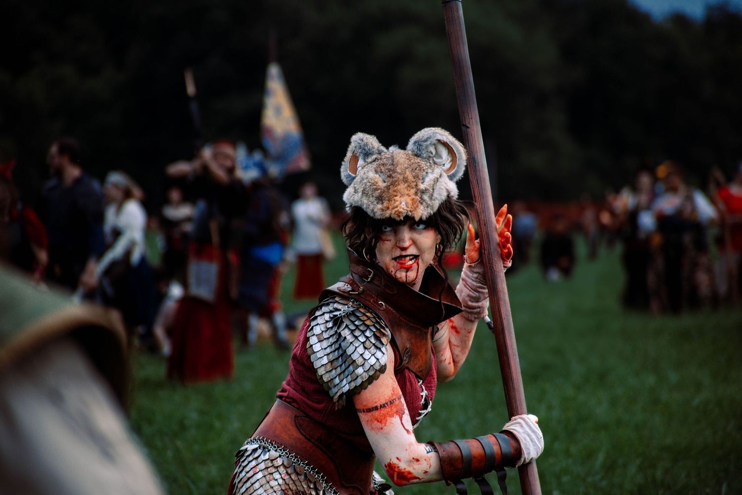Medieval reenactor in ornate armor and helmet wielding a spear during a battle performance.