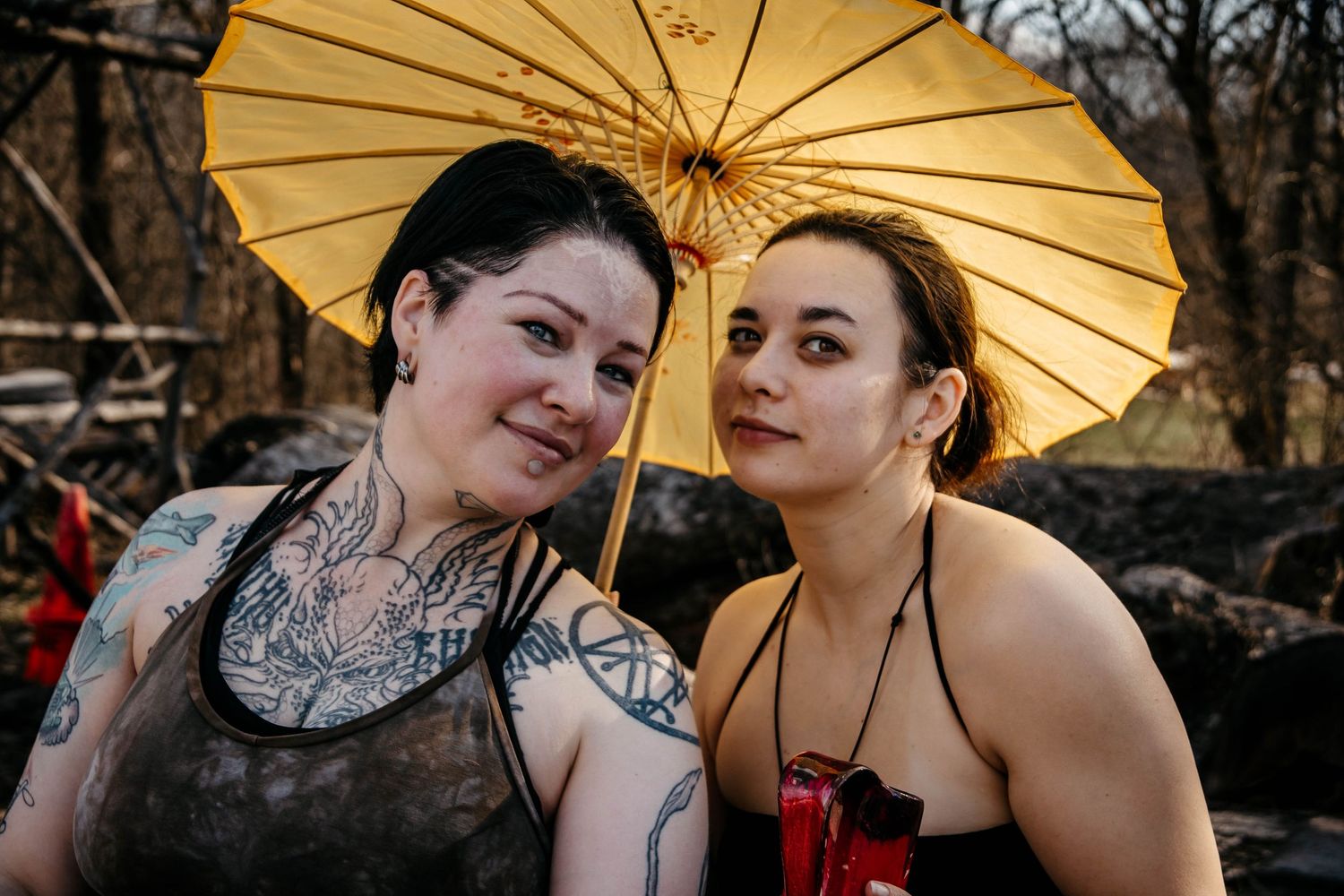 Two people pose intimately with decorative paper parasols in an outdoor setting at dusk.