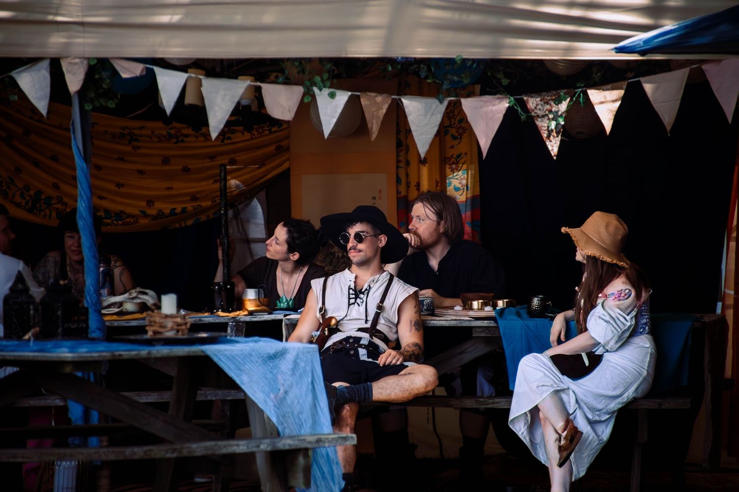 People enjoying drinks and socializing under decorative bunting at an outdoor event venue.