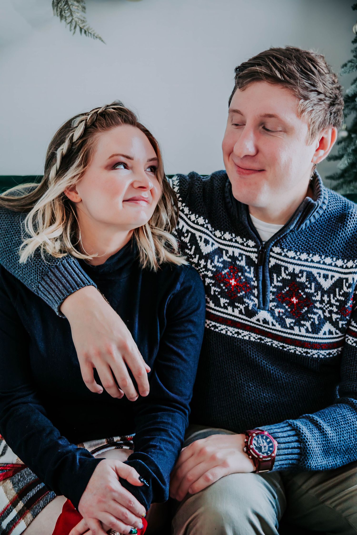 Couple in matching winter sweaters shares intimate moment during photo session.