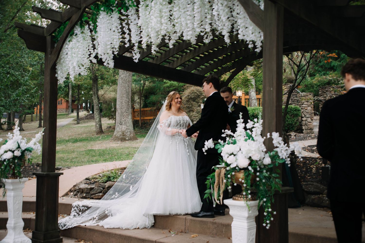 A romantic outdoor wedding scene with a flowing white dress and floral decorations in a rustic garden setting.