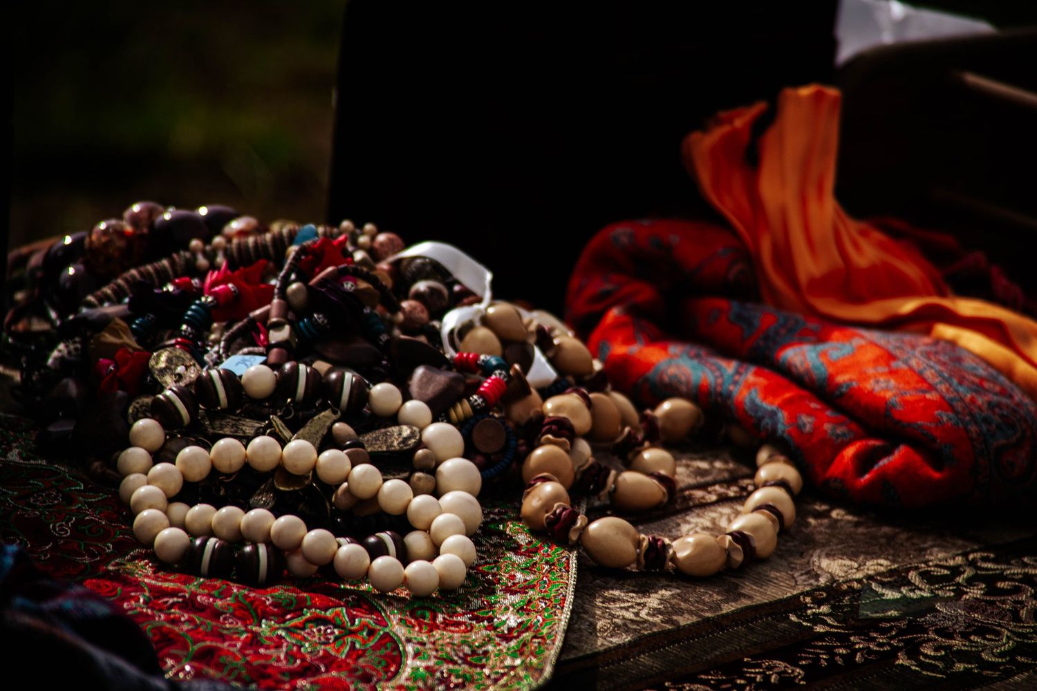 Artistic arrangement of wooden prayer beads with red fabric and dramatic lighting on dark background.