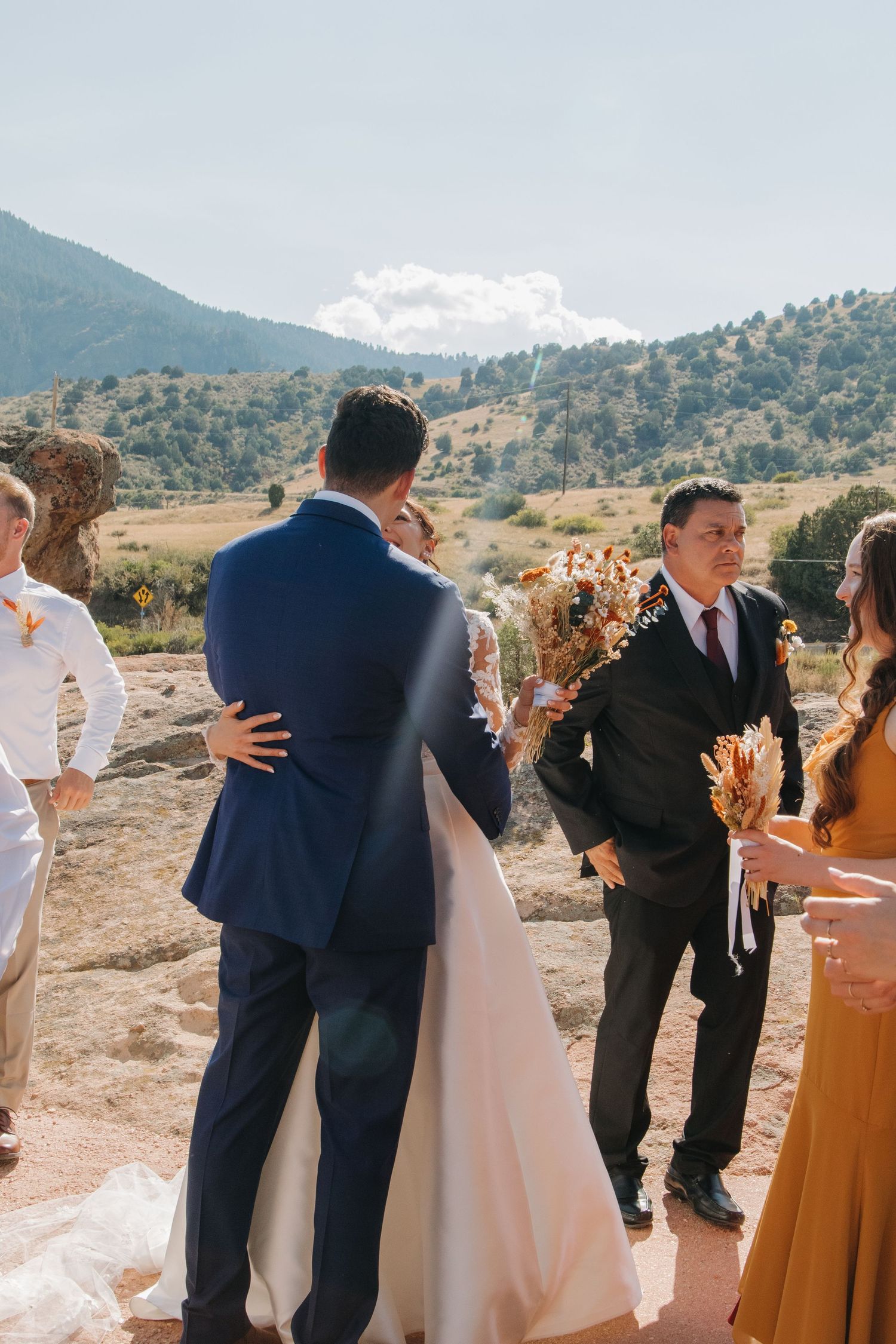 Wedding ceremony participants lined up outdoors with mountain landscape behind them.