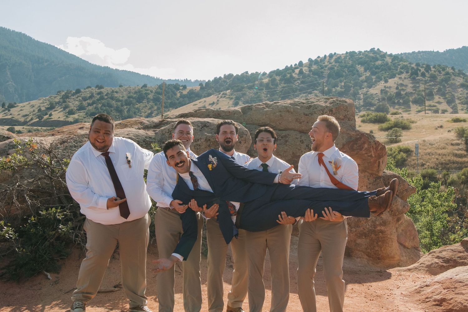Wedding group photo with mountains and scenic red rocks in the background.
