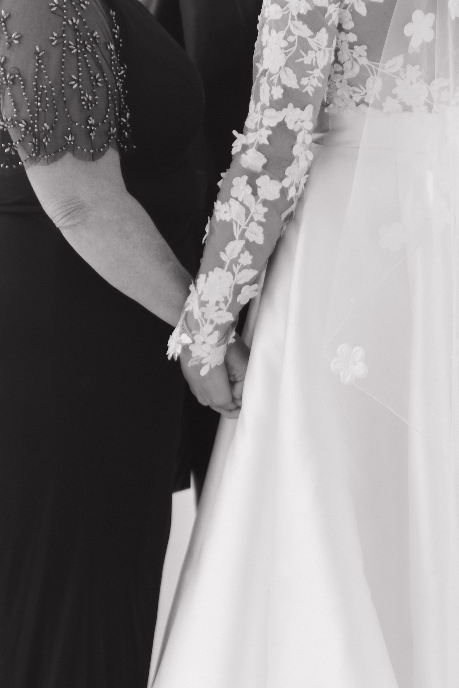 Elegant black and white detail shot of lace sleeve wedding dress and formal attire.