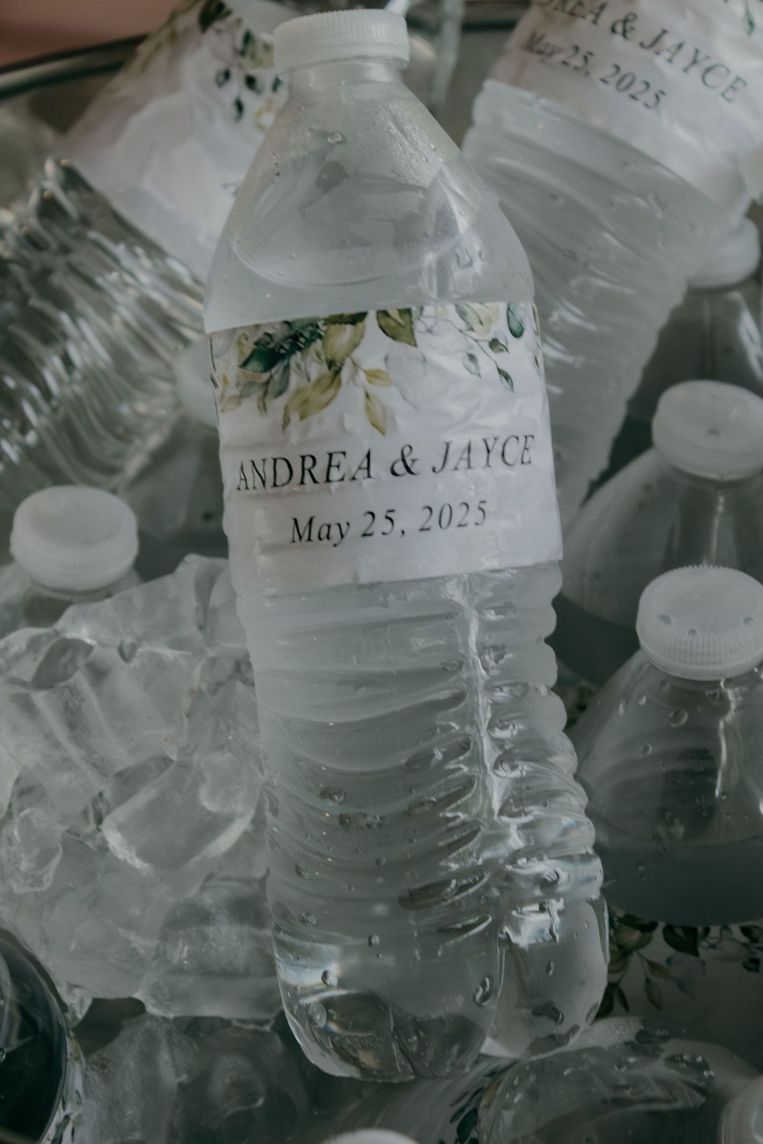 Close-up of personalized water bottles with wedding date and names for a May 2025 celebration.