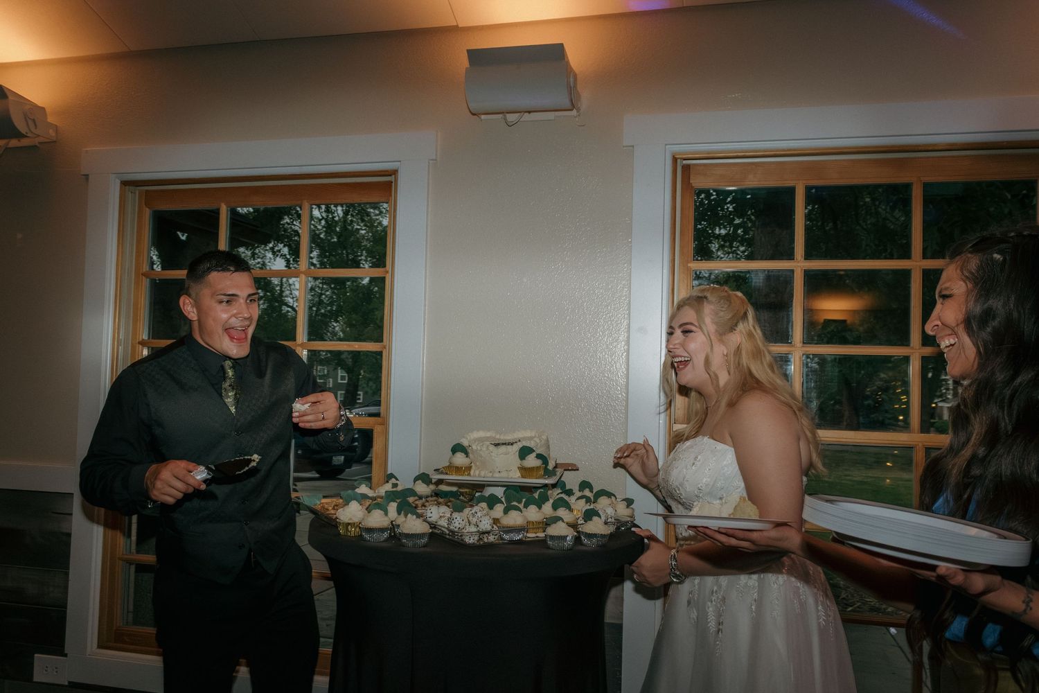 Couple sharing wedding cake in an elegantly lit indoor reception venue.