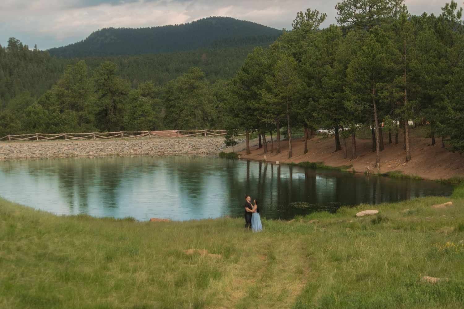 Beautiful mountain landscape with pine trees surrounding a peaceful lake on a cloudy day.