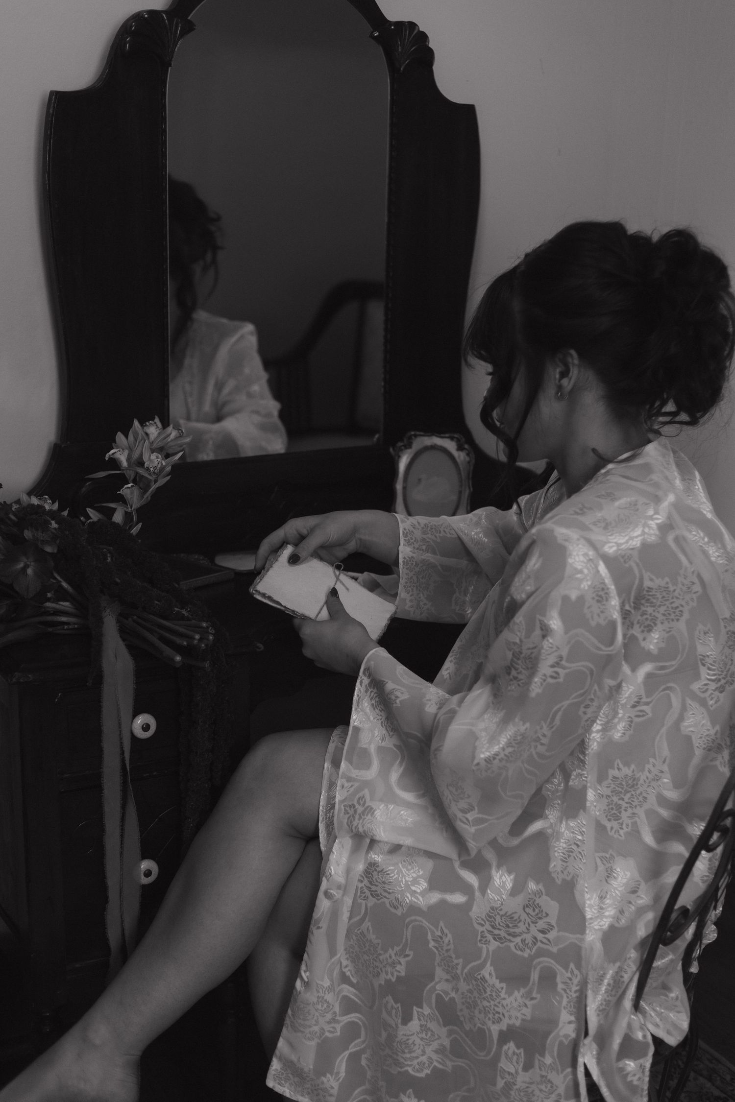 Woman in a white lace robe getting ready in front of a mirror.