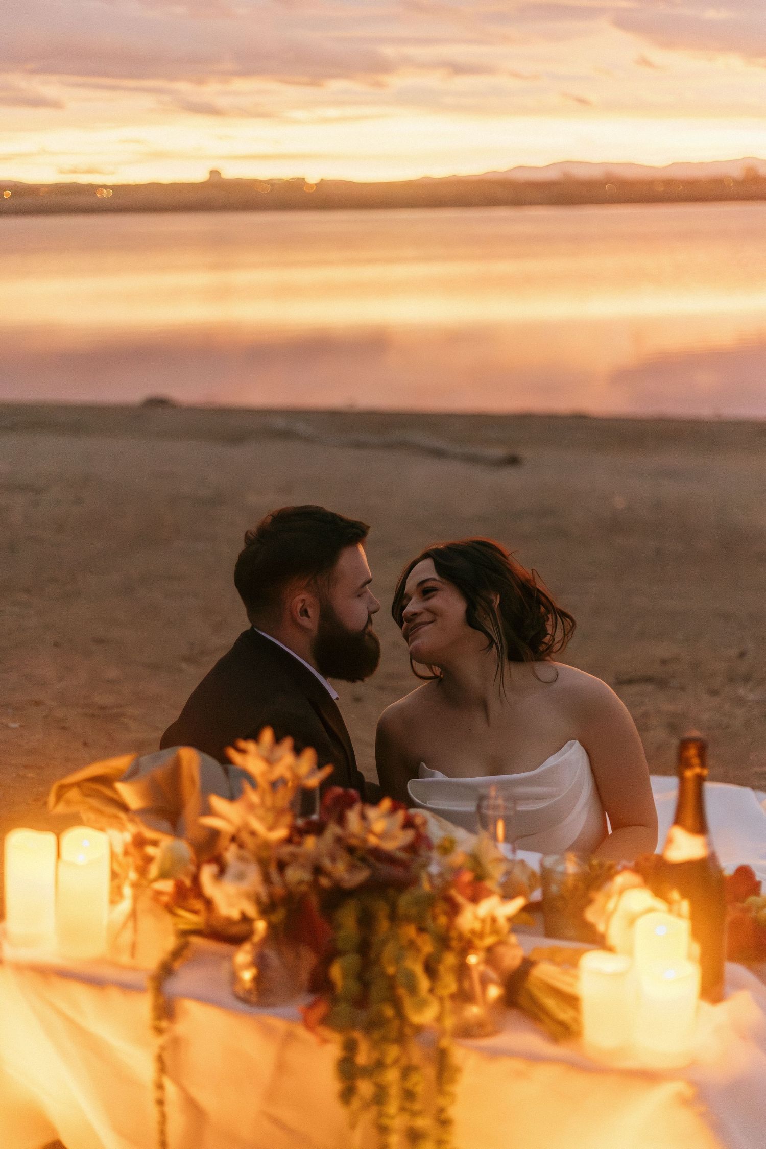 A wedding couple shares an intimate moment at their sunset reception with floral centerpieces.