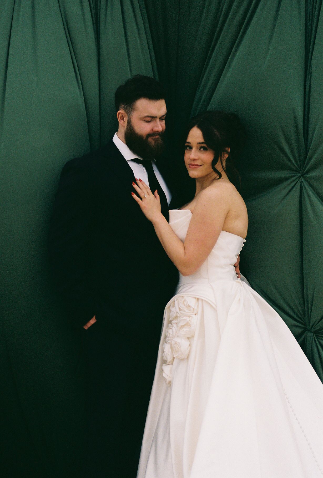 A wedding portrait against an emerald green tufted backdrop.