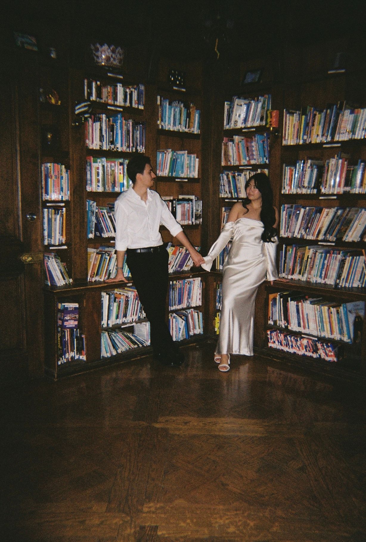 Dancers perform romantic moves in a library setting surrounded by rows of books.