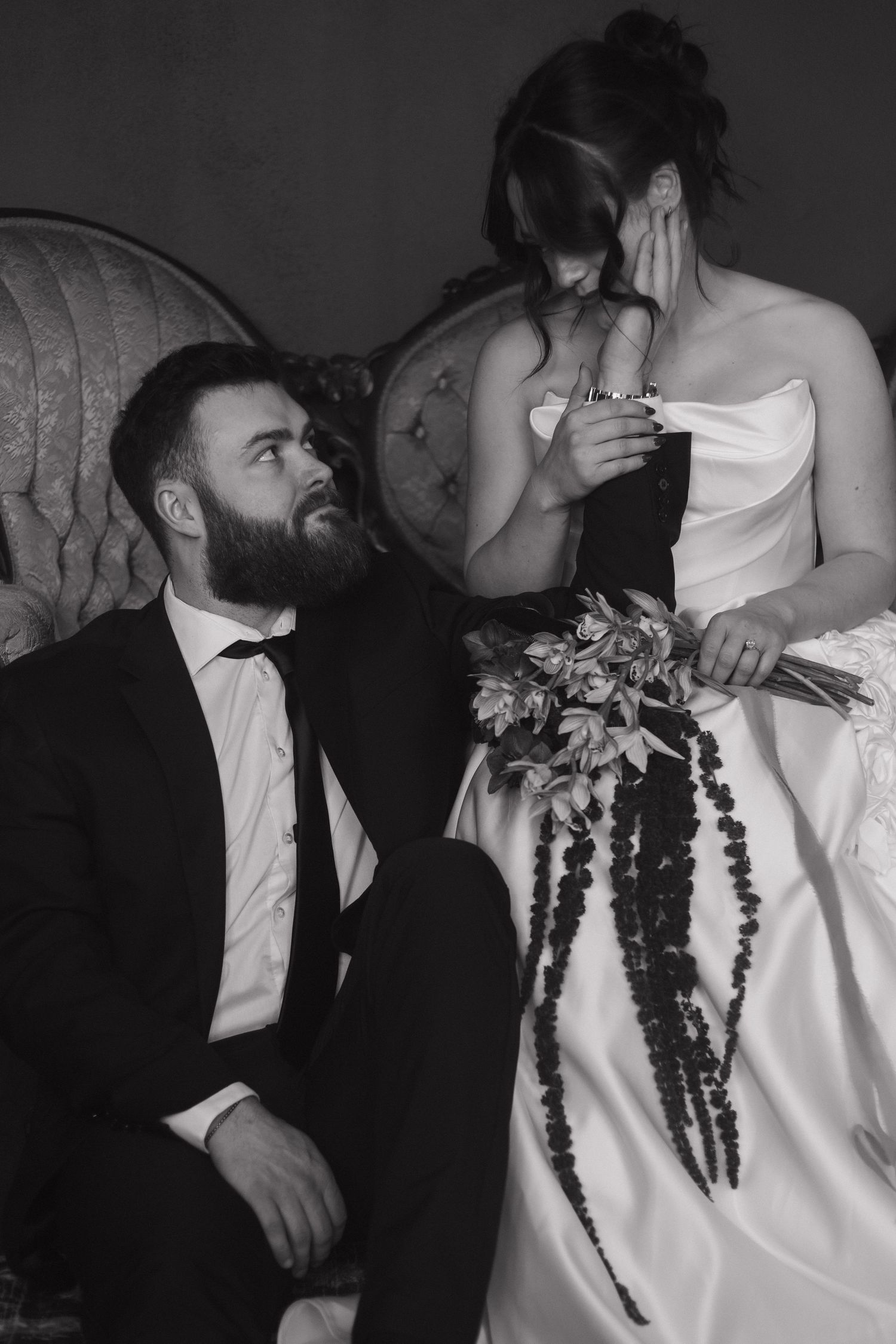 A black and white wedding photo showing a couple in formal attire with floral decorations.