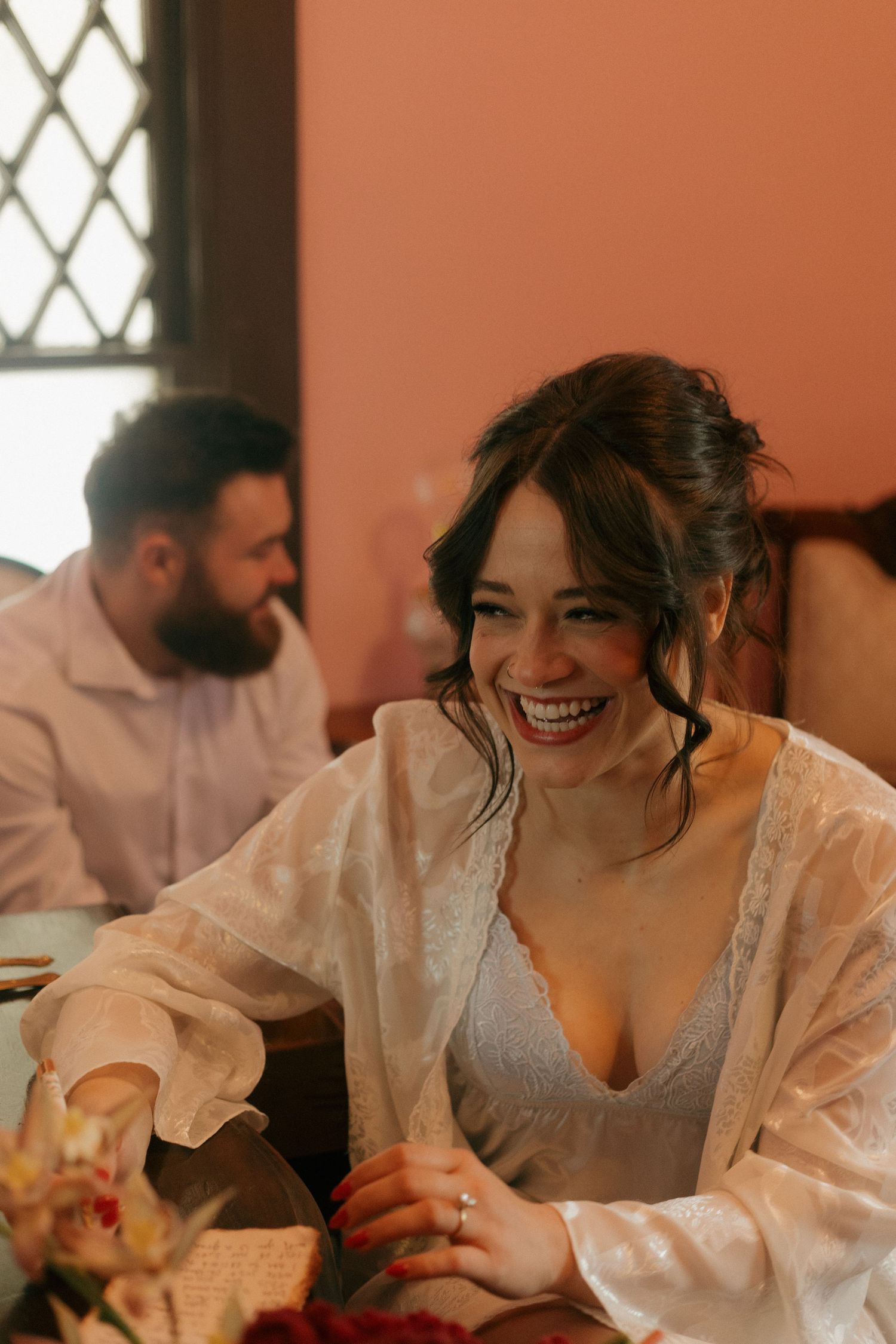 A person in a white lace top laughs joyfully during a candid moment.