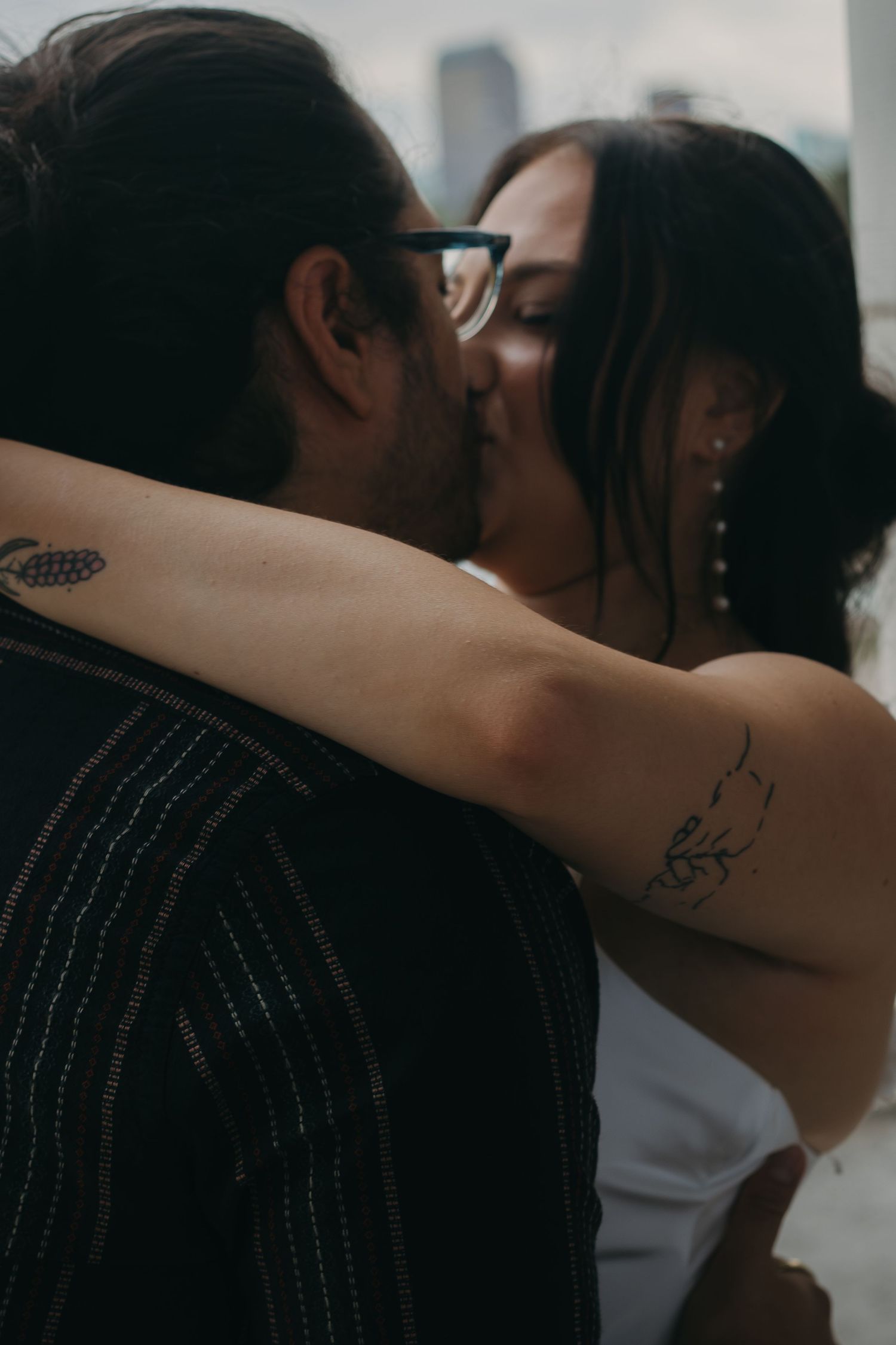An intimate moment between two people showing arm tattoos and embracing.