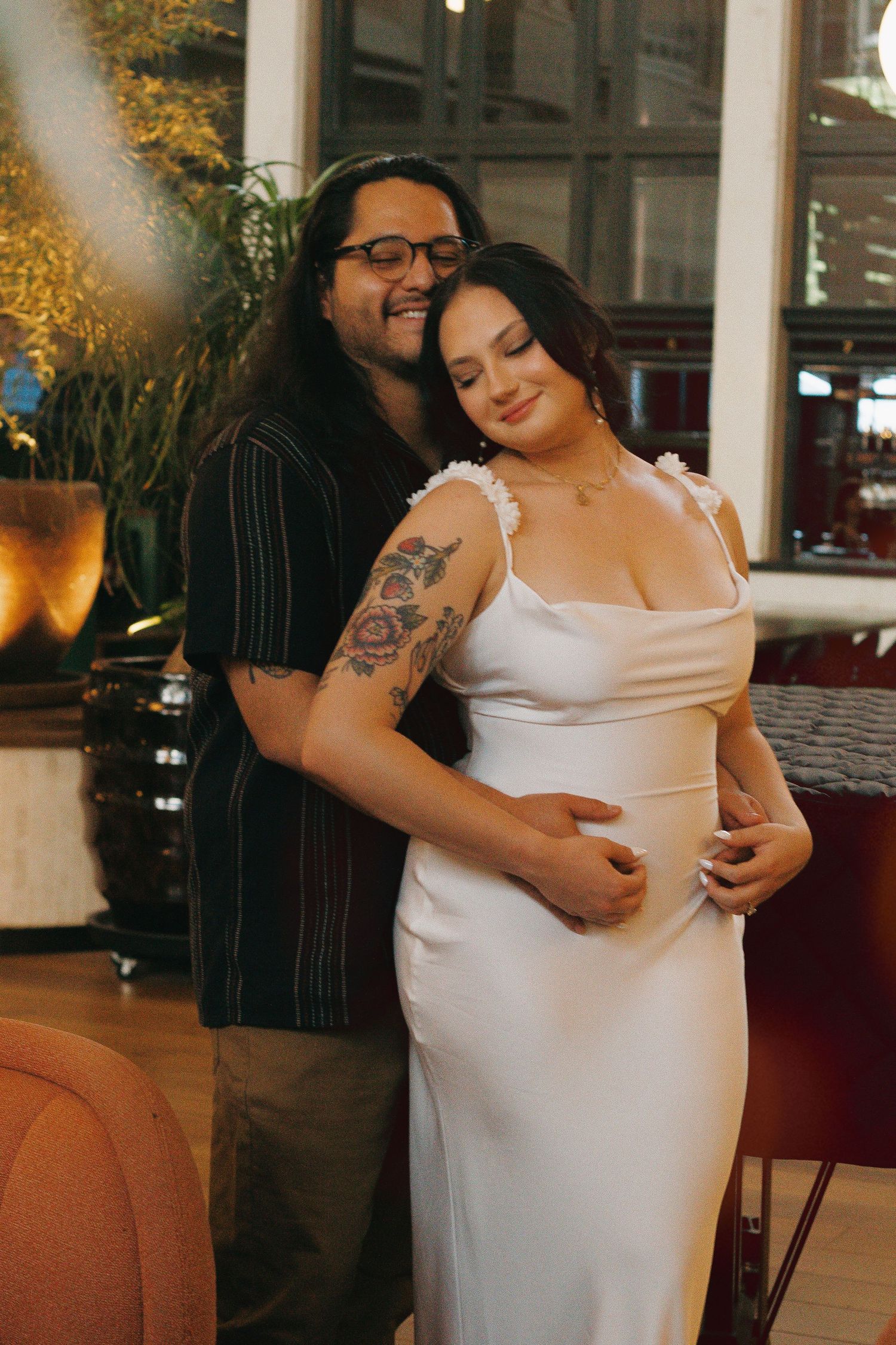 A romantic couple sharing an intimate embrace in a white dress and dark outfit at a restaurant.