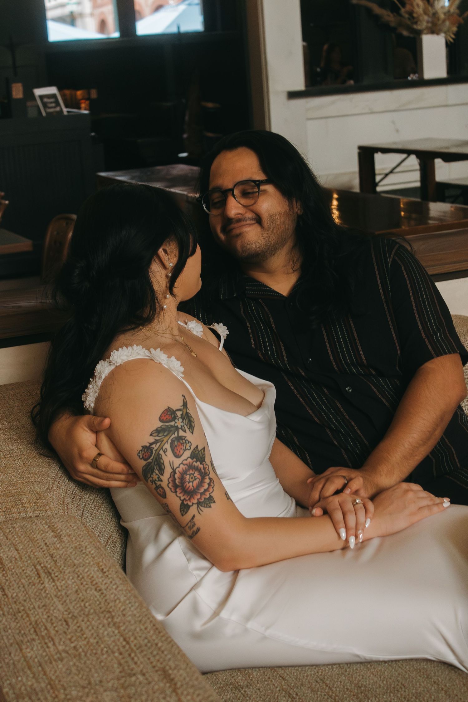 An intimate indoor portrait showing a couple relaxing together in casual attire.