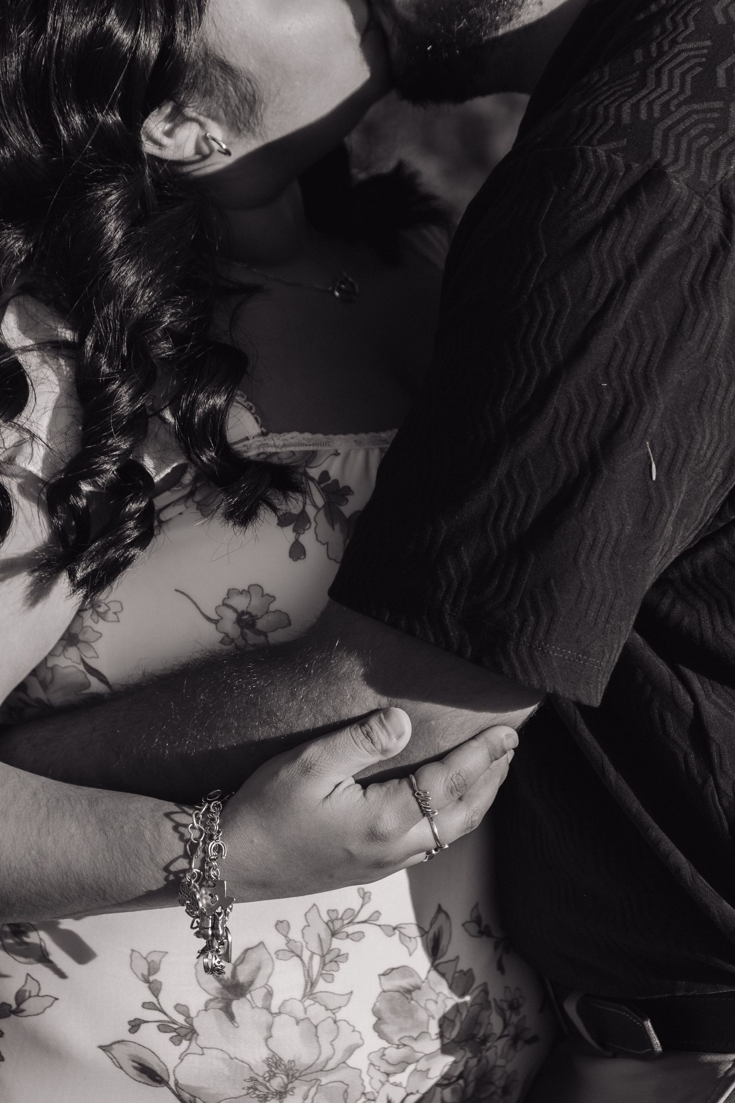 An artistic black and white photo shows a couple's hands intertwined during an intimate moment.