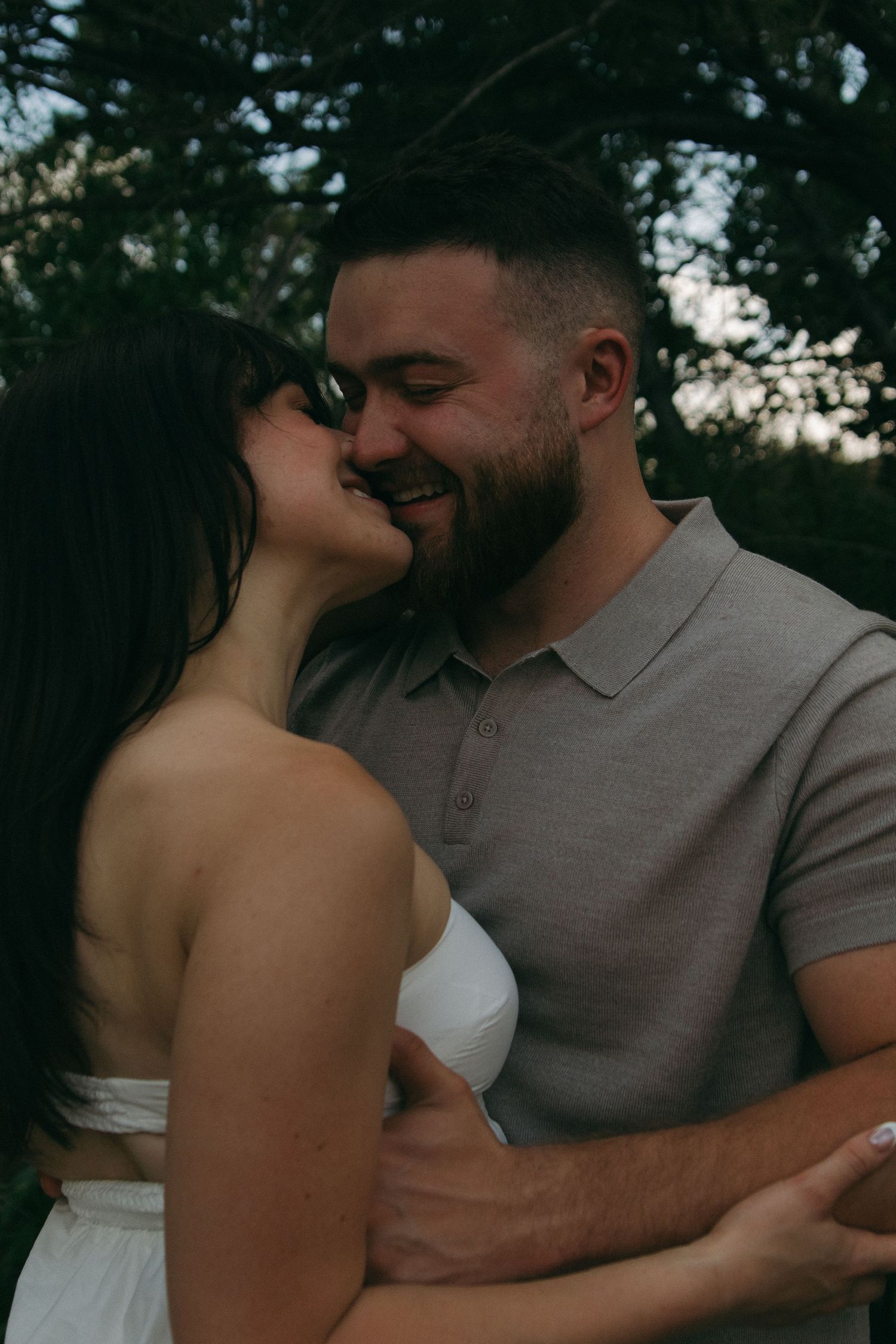 Intimate outdoor portrait of couple embracing against natural background.