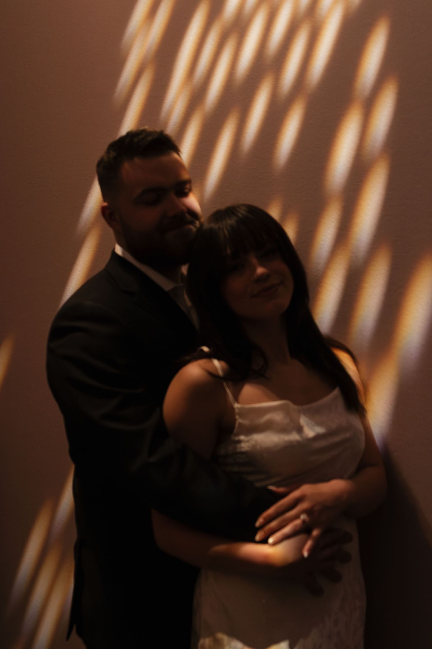 Dance partners embrace during an intimate slow dance with dramatic shadows on the wall.