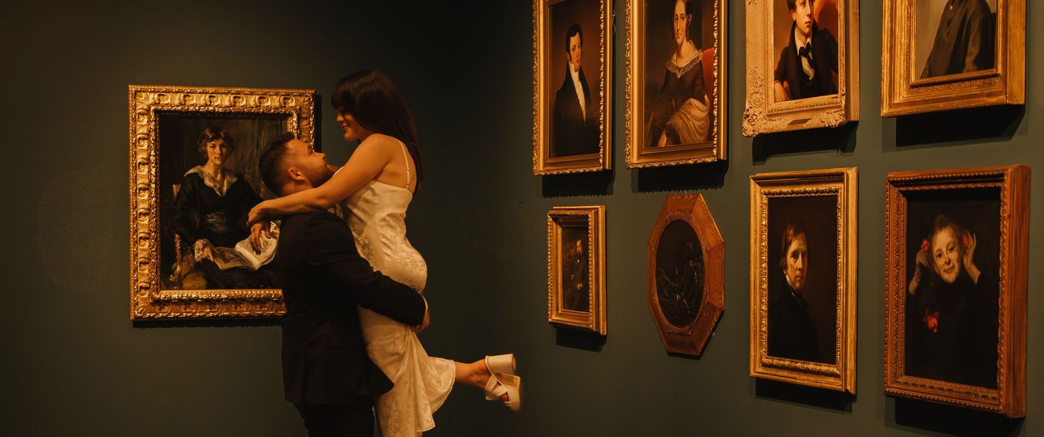 A gallery wall filled with gold-framed portraits in atmospheric lighting.