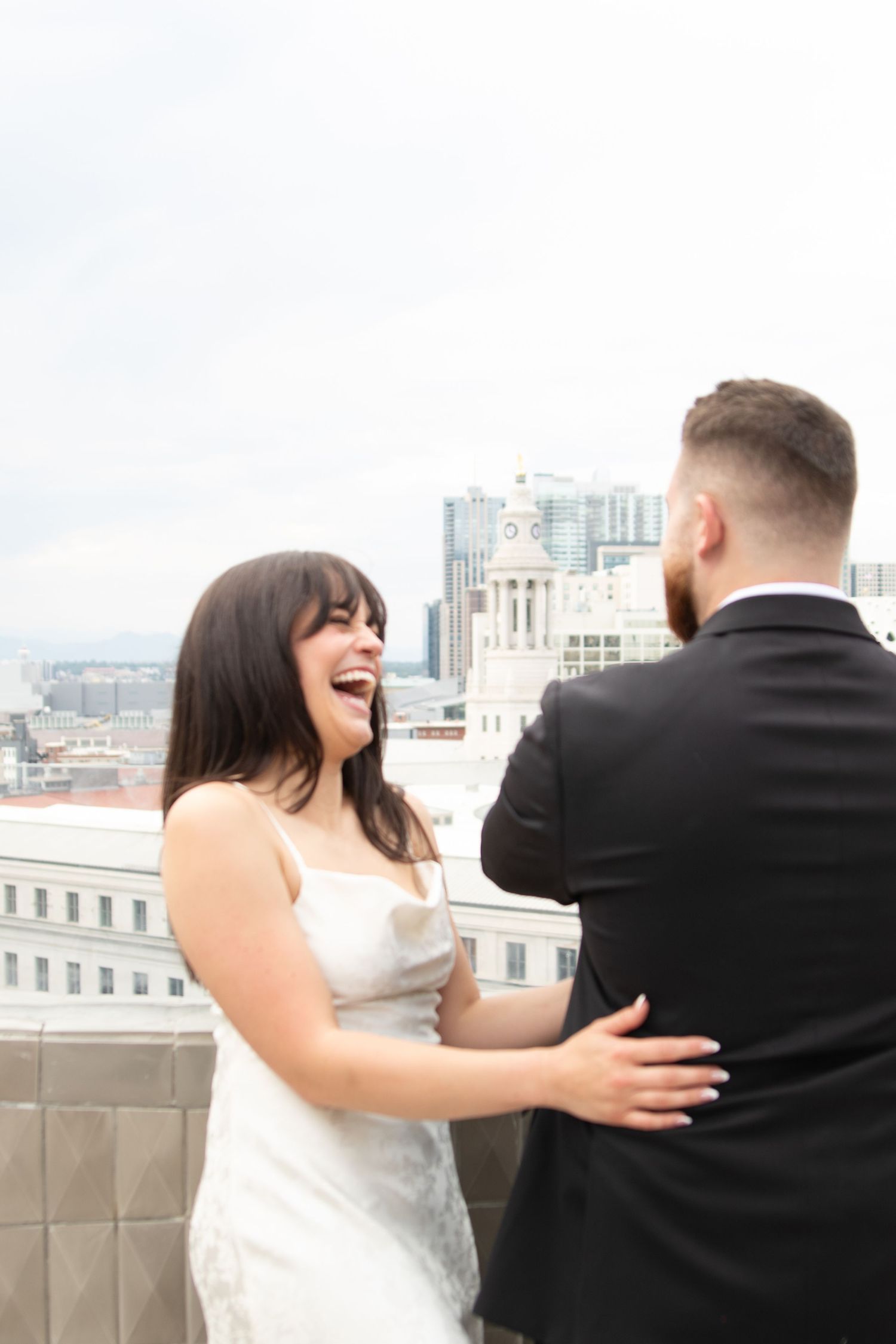 Couple playfully interacting on urban rooftop with city skyline.