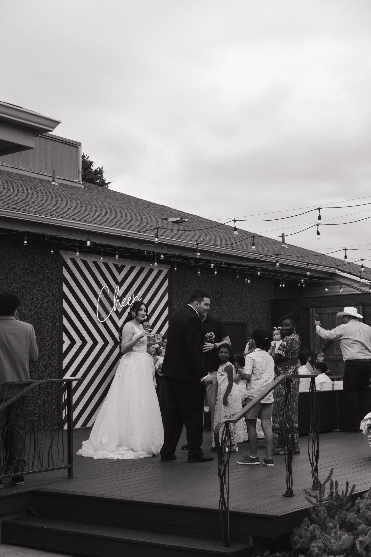 Bride and groom share a moment on a decorated outdoor stage at their wedding reception in black and white.