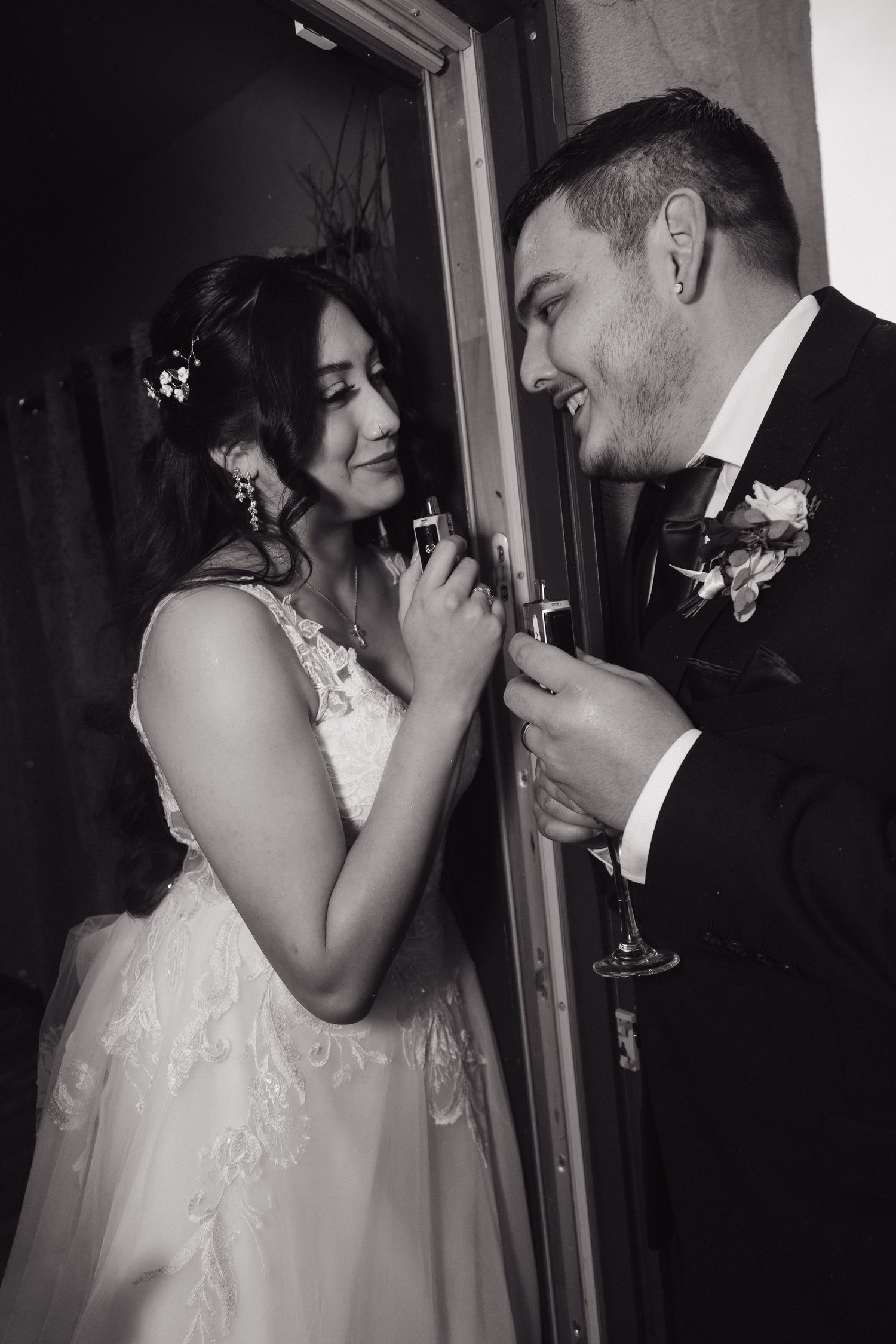 Black and white photo of smiling bride and groom sharing a joyful moment together at their wedding reception.