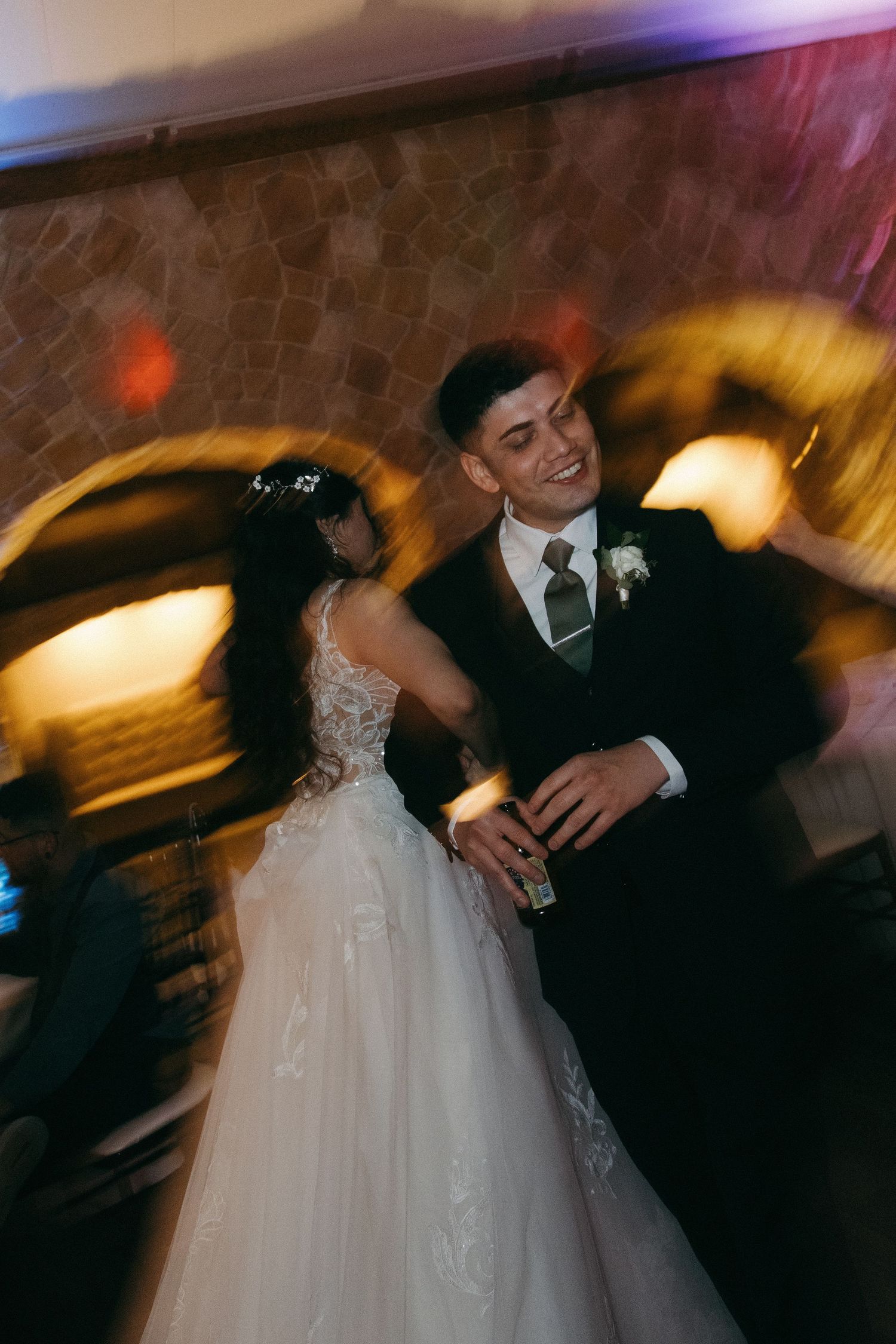 Bride and groom share a joyful first dance with motion blur at wedding reception.