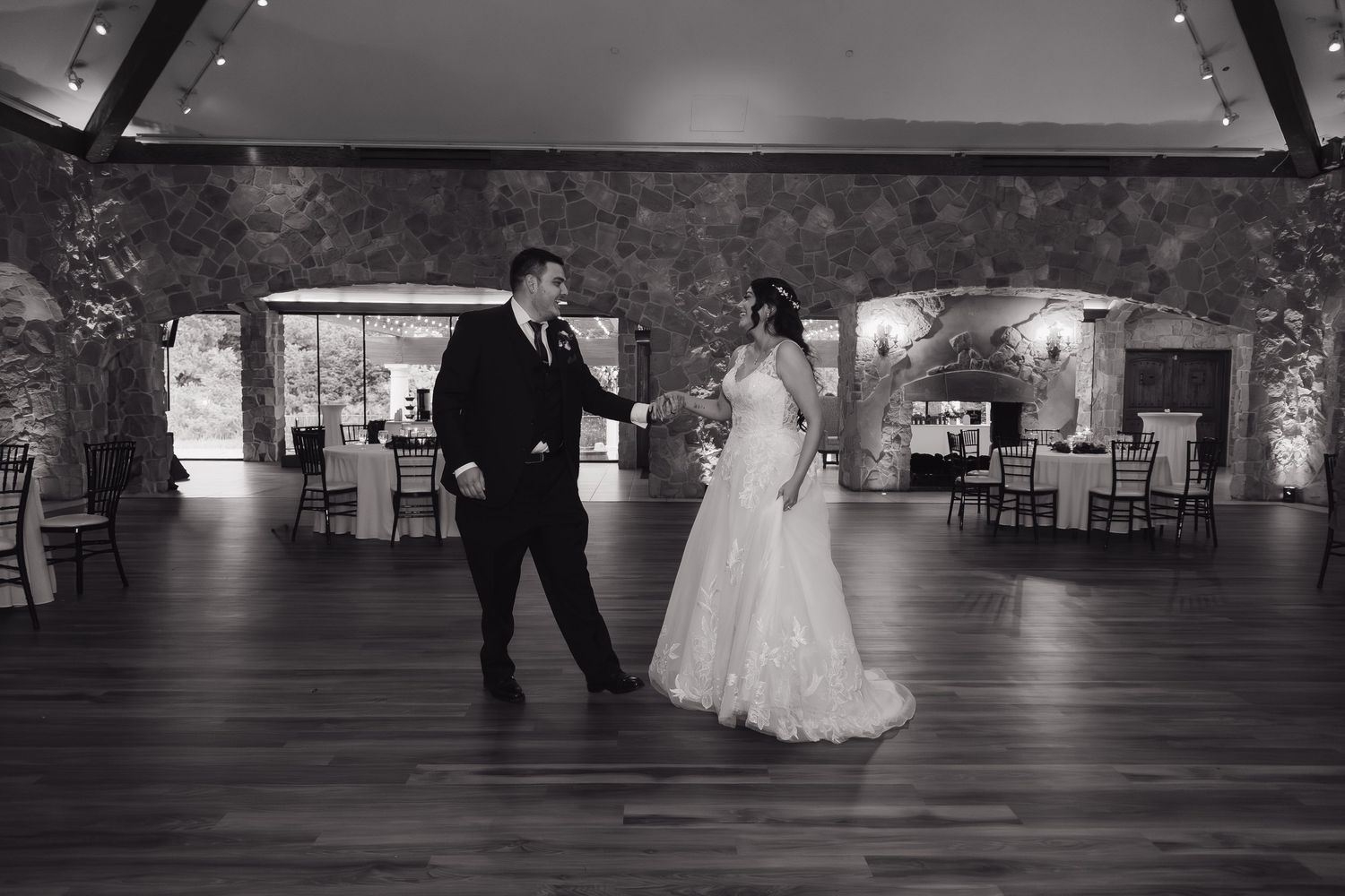 Black and white photo of bride and groom sharing their first dance in elegant ballroom.