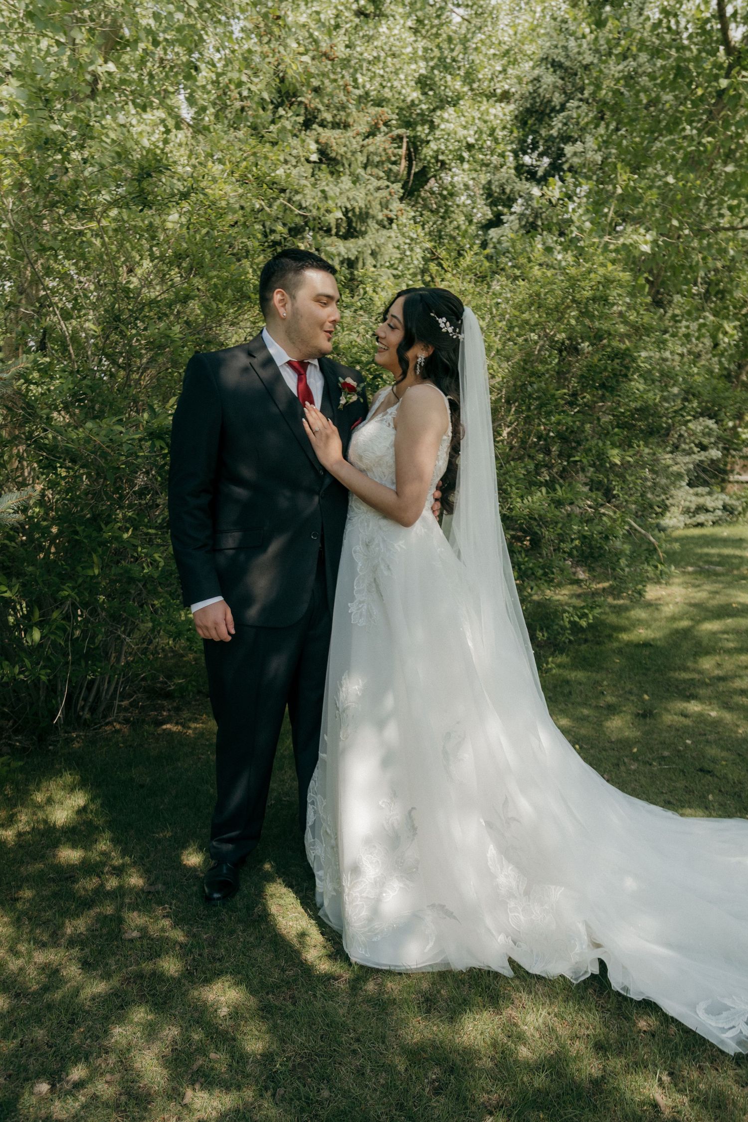 Bride and groom sharing a romantic moment in a lush green garden setting.