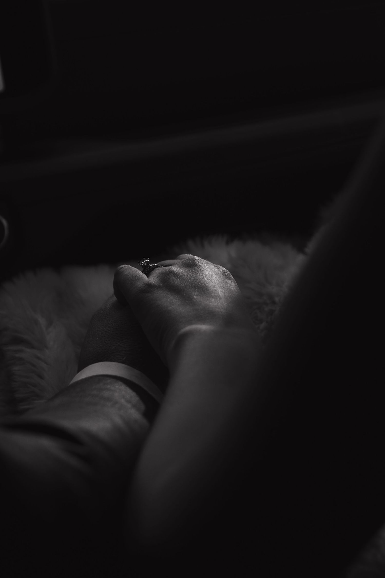 A black and white artistic photograph shows a person resting in deep shadows with soft lighting.