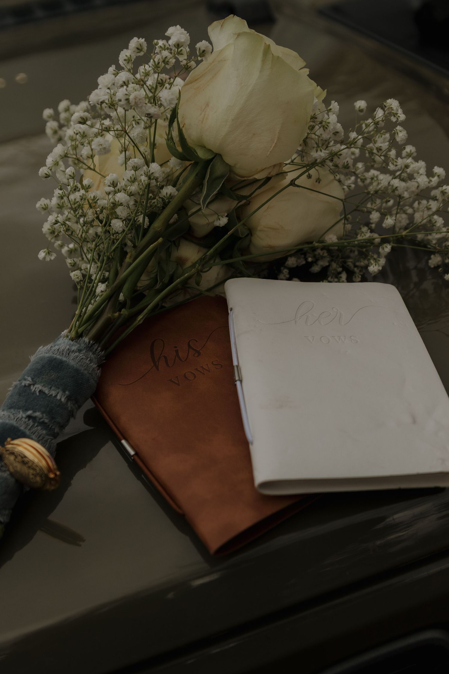 White roses and baby's breath flowers arranged with wedding vow books.